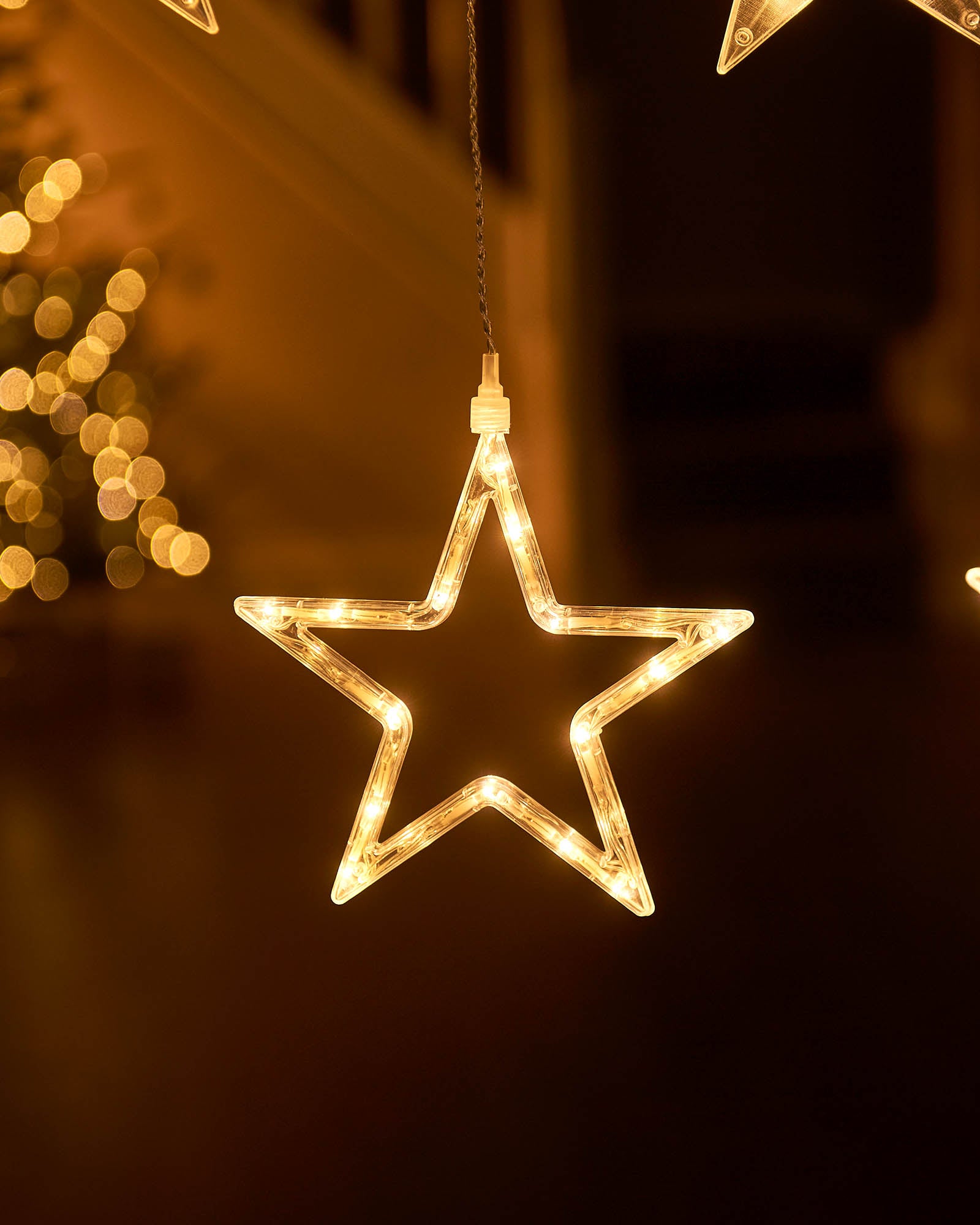 Close-up of a hollow warm white star light hanging from a curtain light display