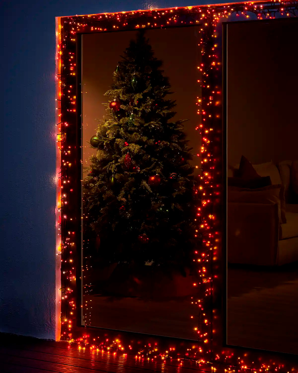 Autumn colour cluster lights framing a patio door with a Christmas tree visible inside.