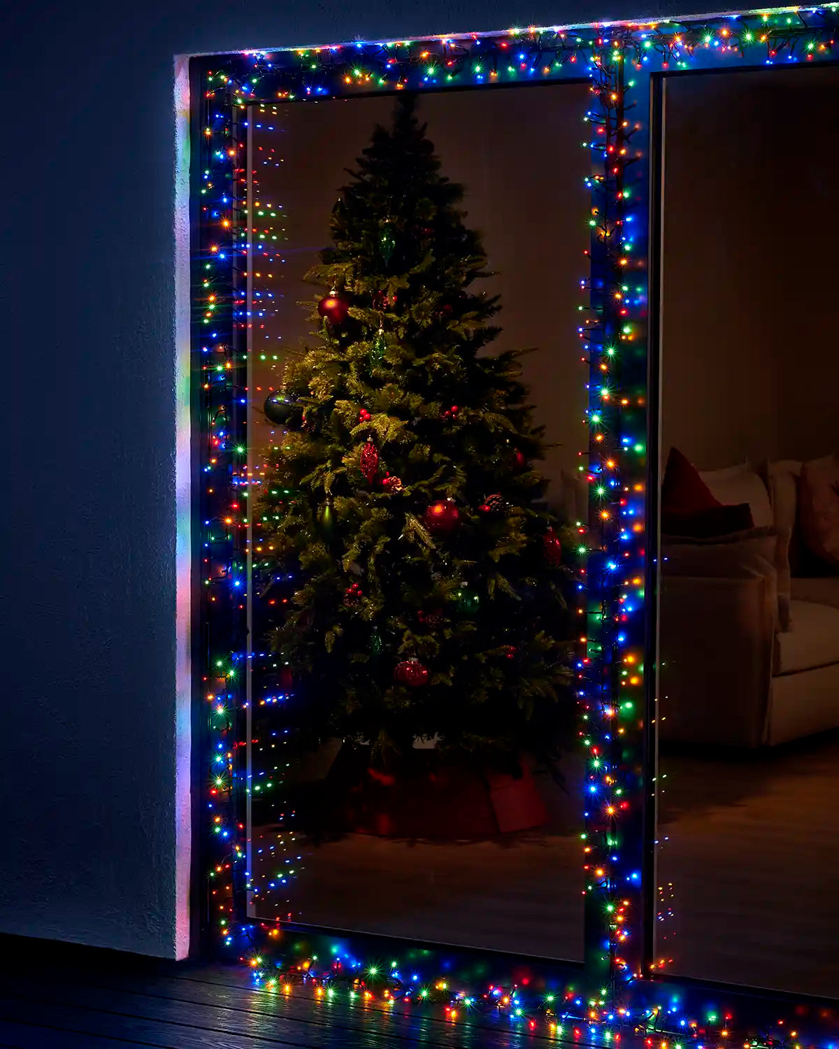 Multi colour cluster lights framing a patio door with a Christmas tree visible inside.