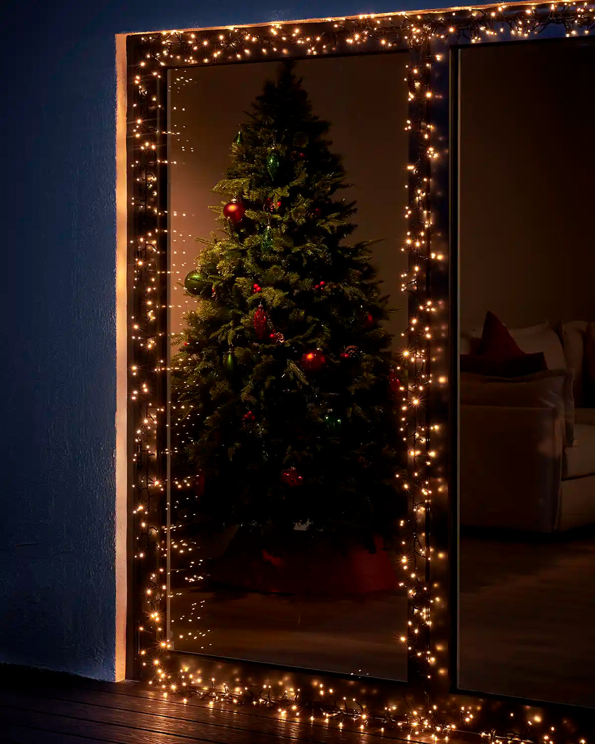 Warm white cluster lights framing a patio door with a Christmas tree visible inside.