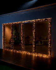 Warm white Home Series cluster lights displayed around large patio doors at night.