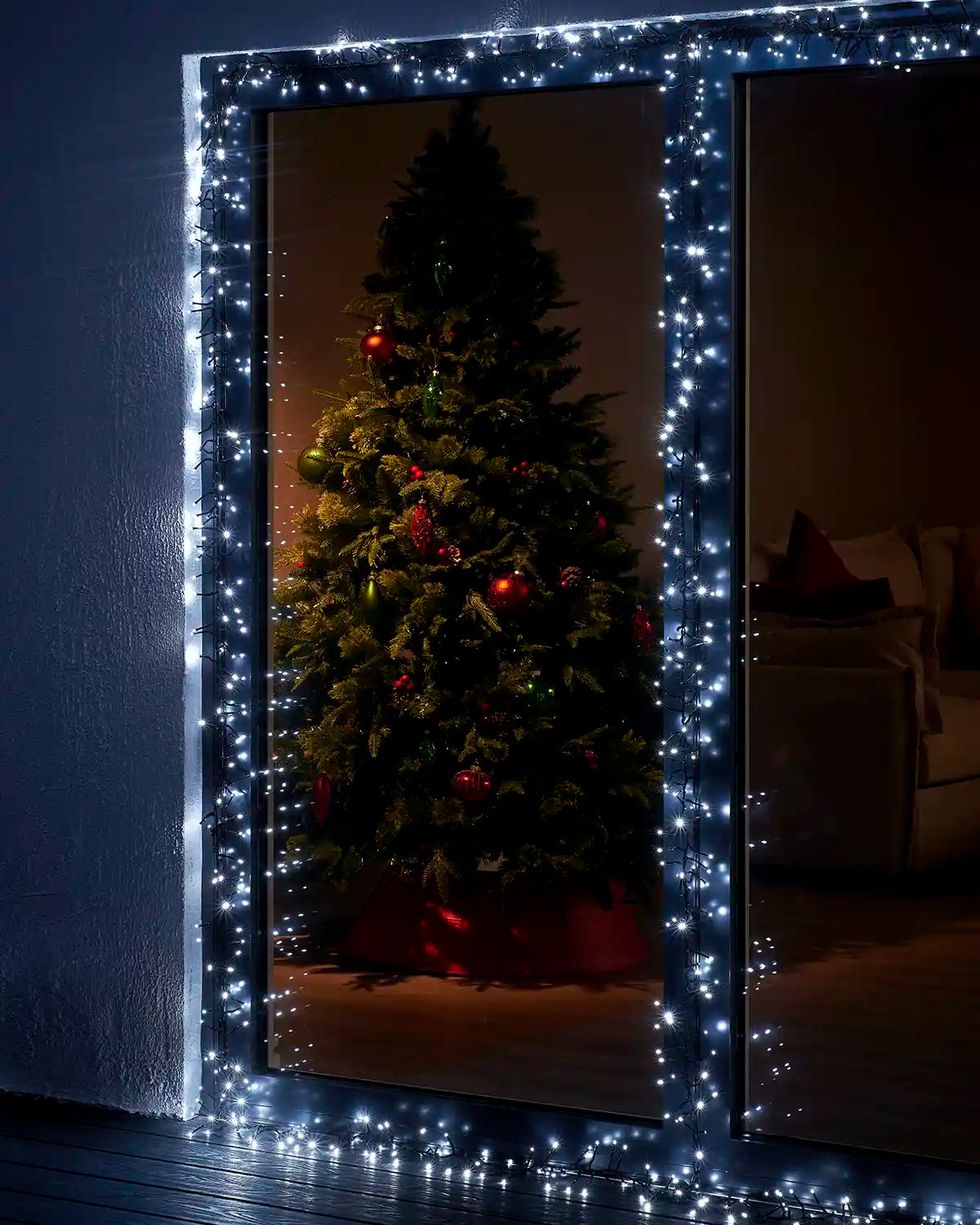 White cluster lights framing a patio door with a Christmas tree visible inside.