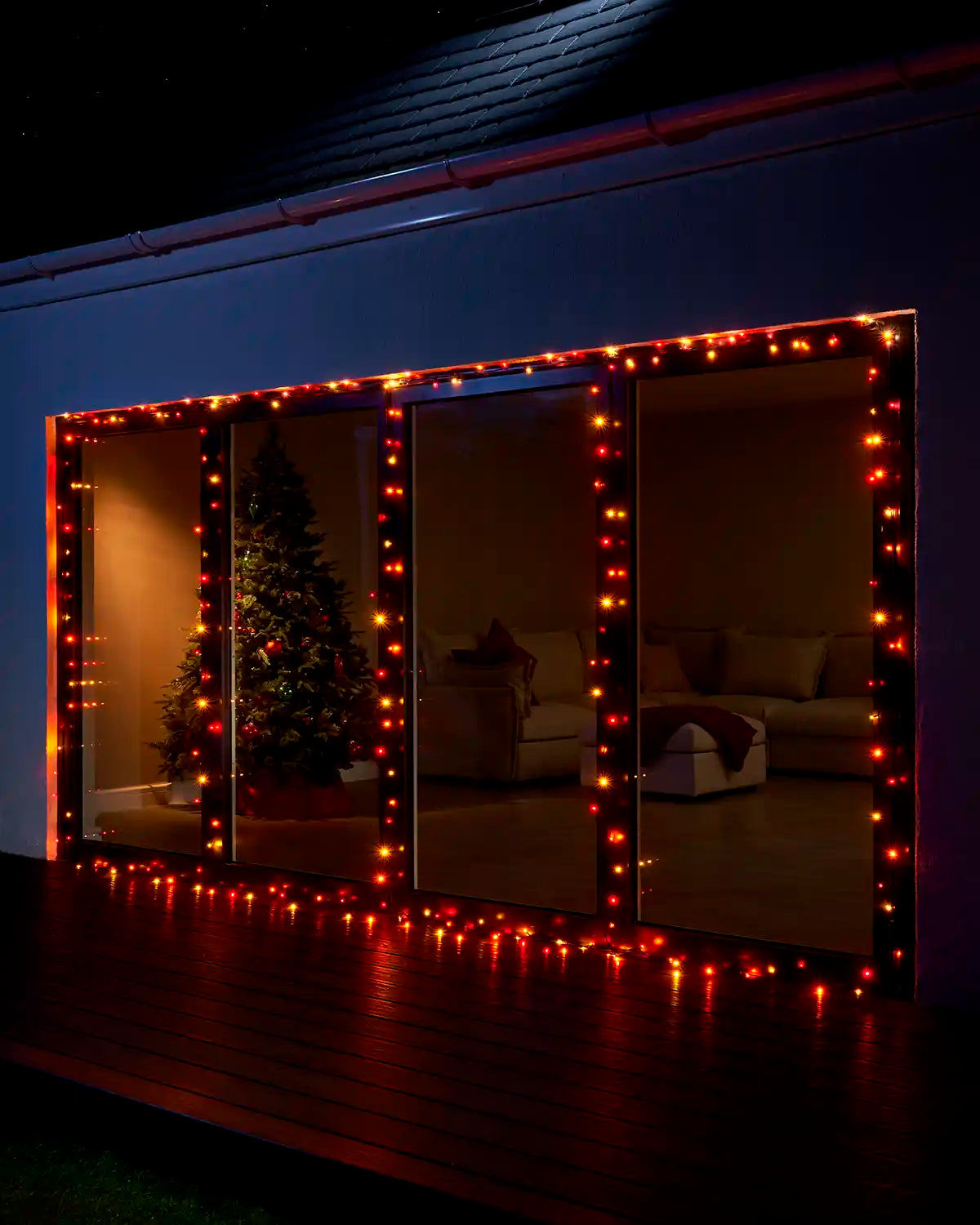 Autumn colour Home Series string lights displayed around large patio doors at night.