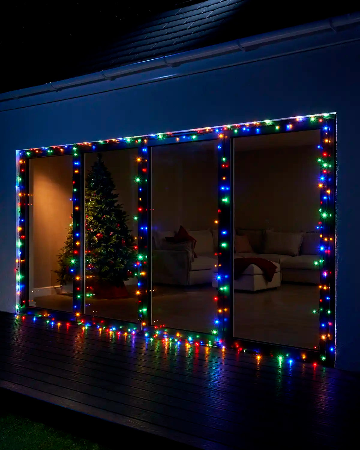 Multi colour Home Series string lights displayed around large patio doors at night.