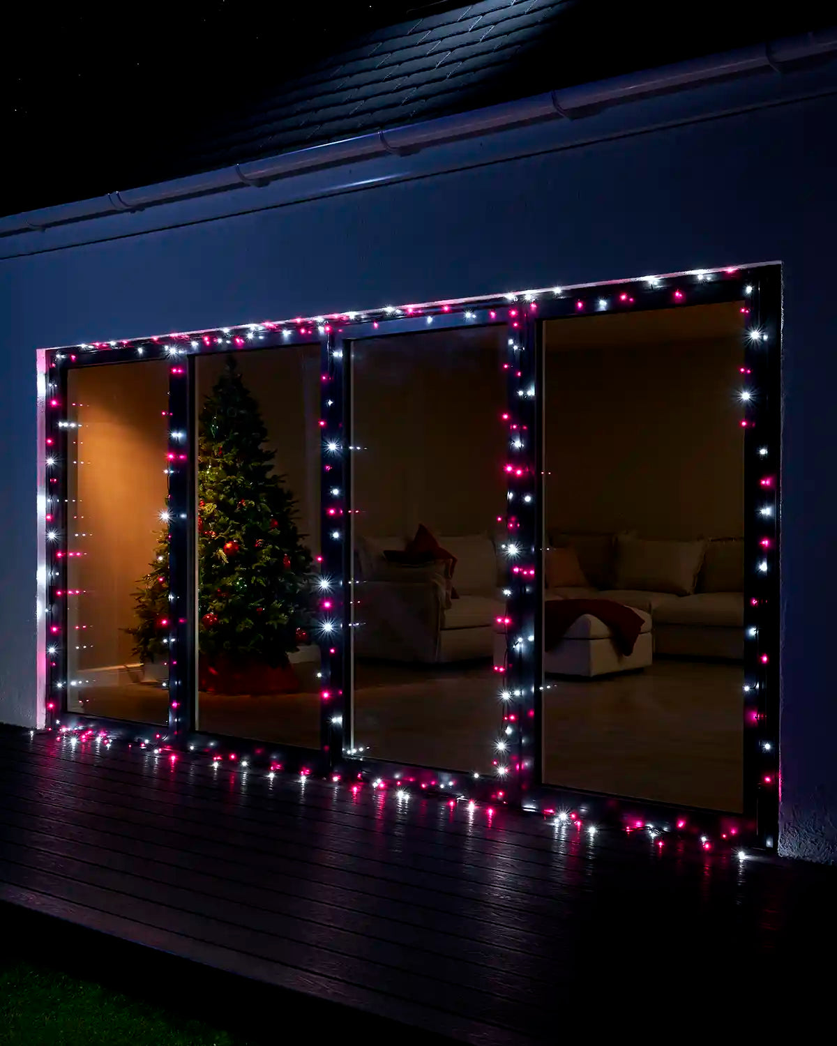 Pink and white Home Series string lights displayed around large patio doors at night.