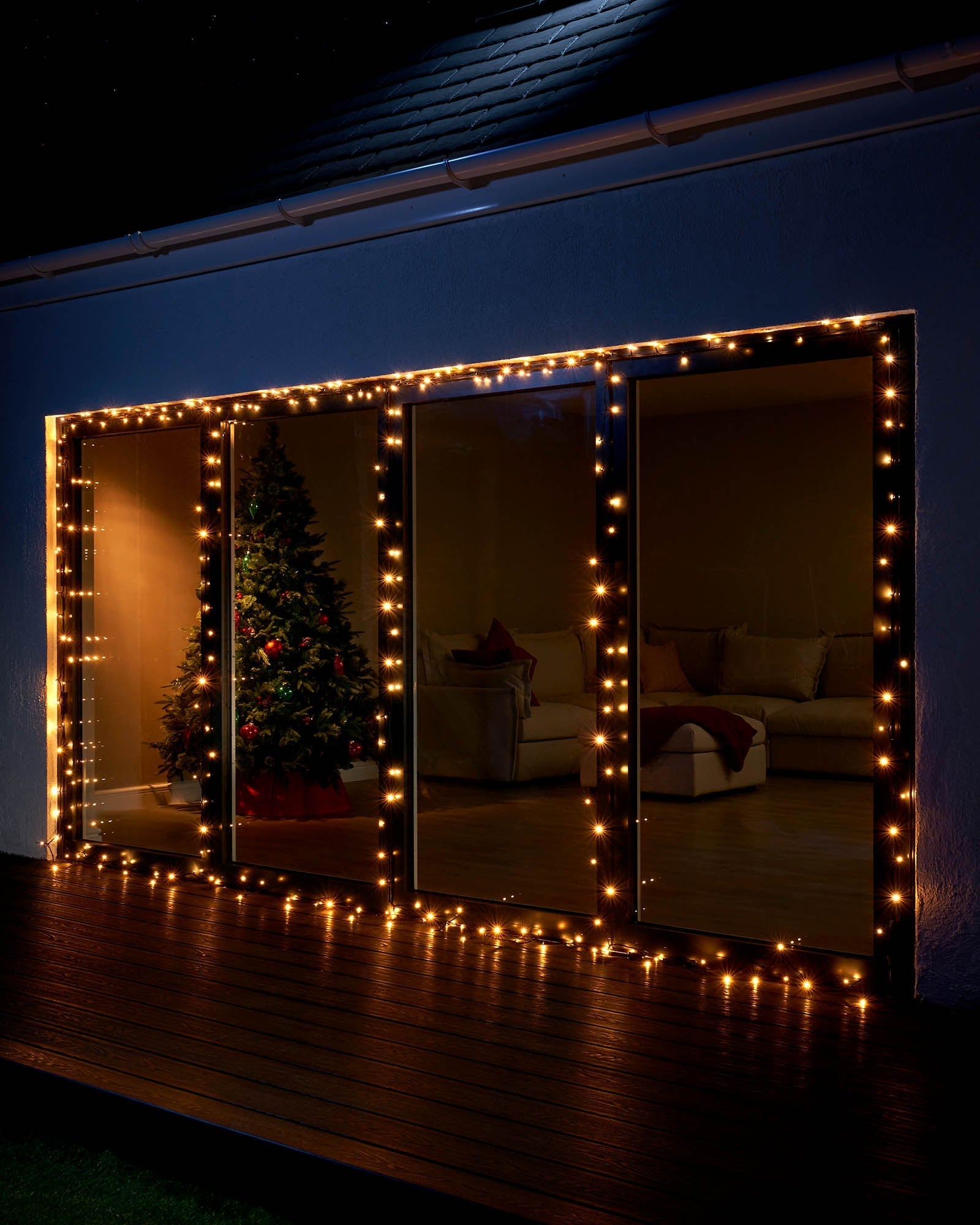 Warm white Home Series string lights displayed around large patio doors at night.