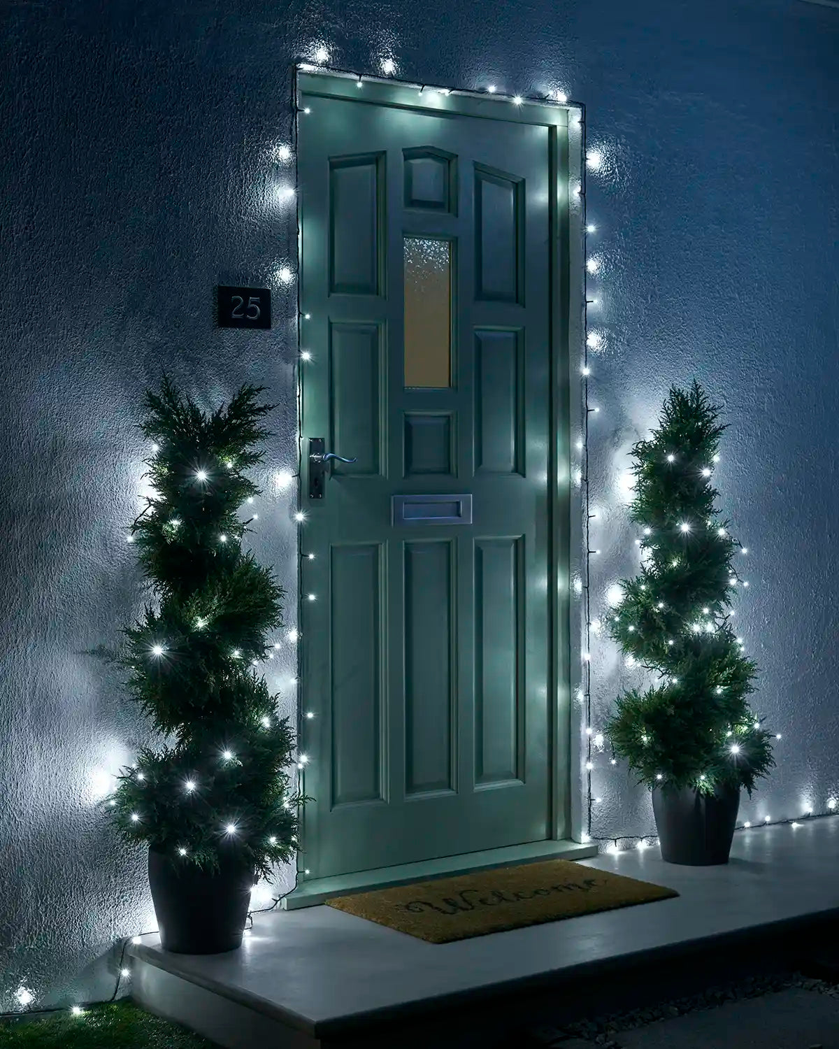 White Home Series string lights framing a front door with two lit potted trees.