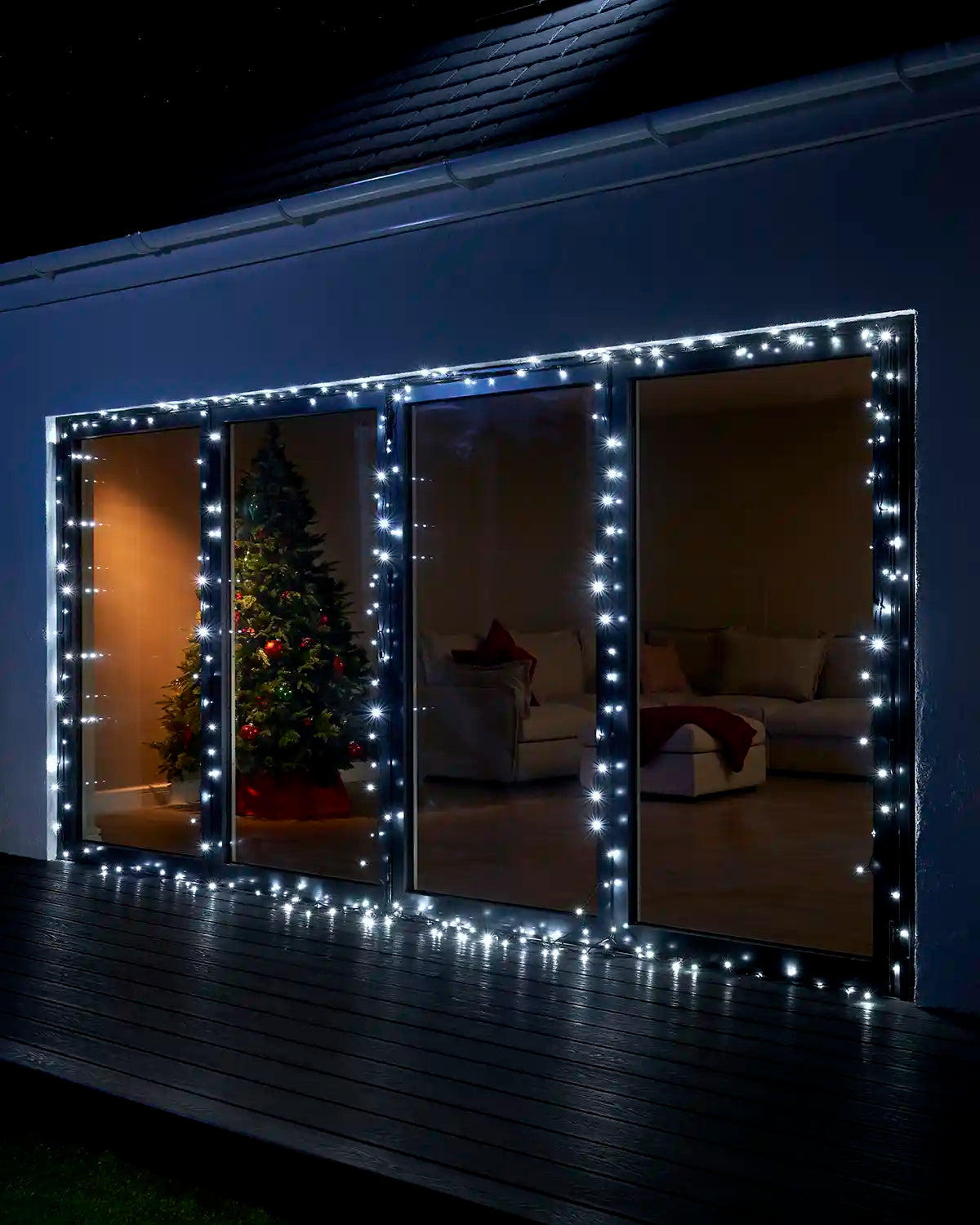 White Home Series string lights displayed around large patio doors at night.