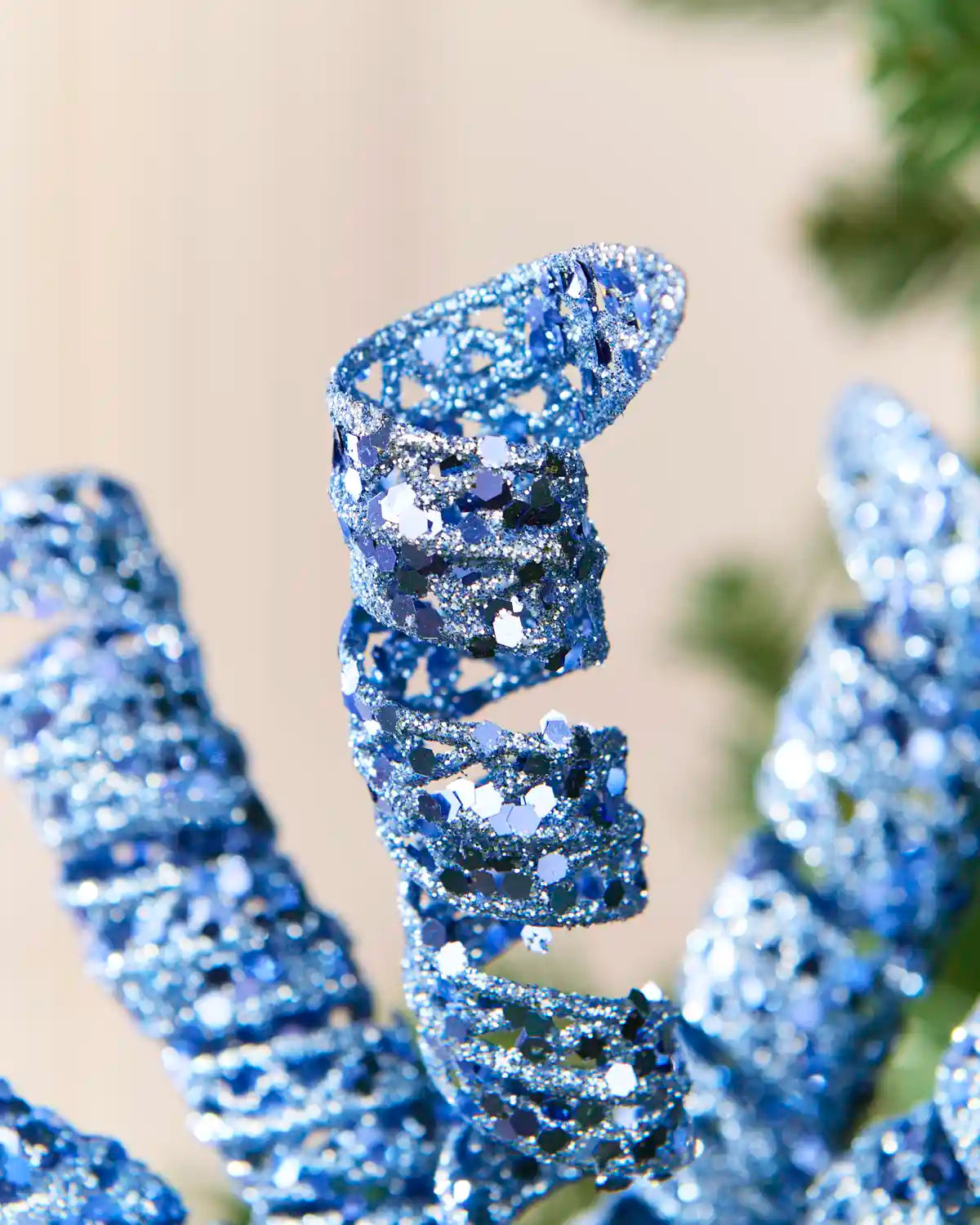 Detailed view of an ice blue glitter spiral pick showing its curled shape and textured reflective finish.