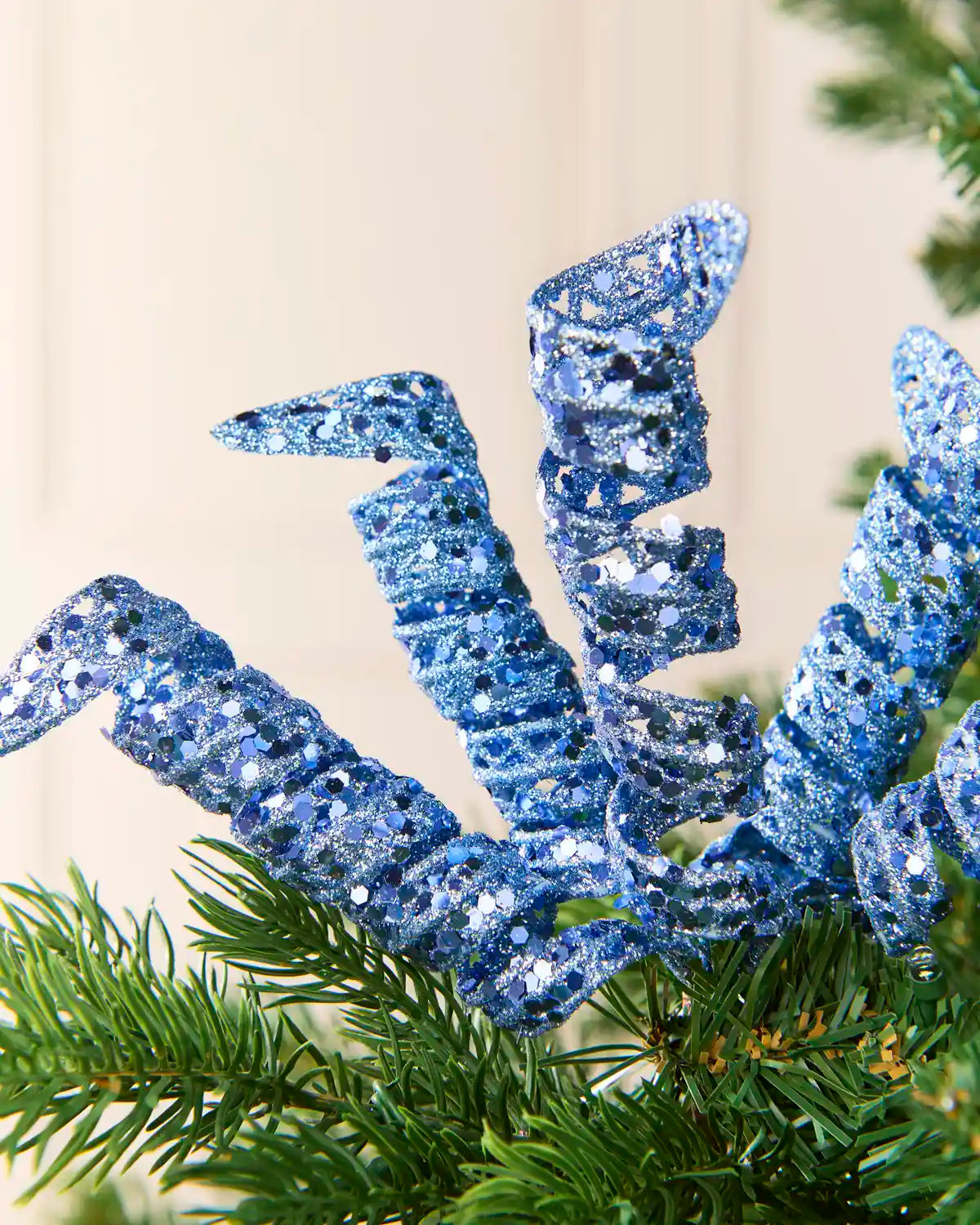 Close-up of ice blue glitter spiral picks showing curled openwork shapes and reflective sequin details.