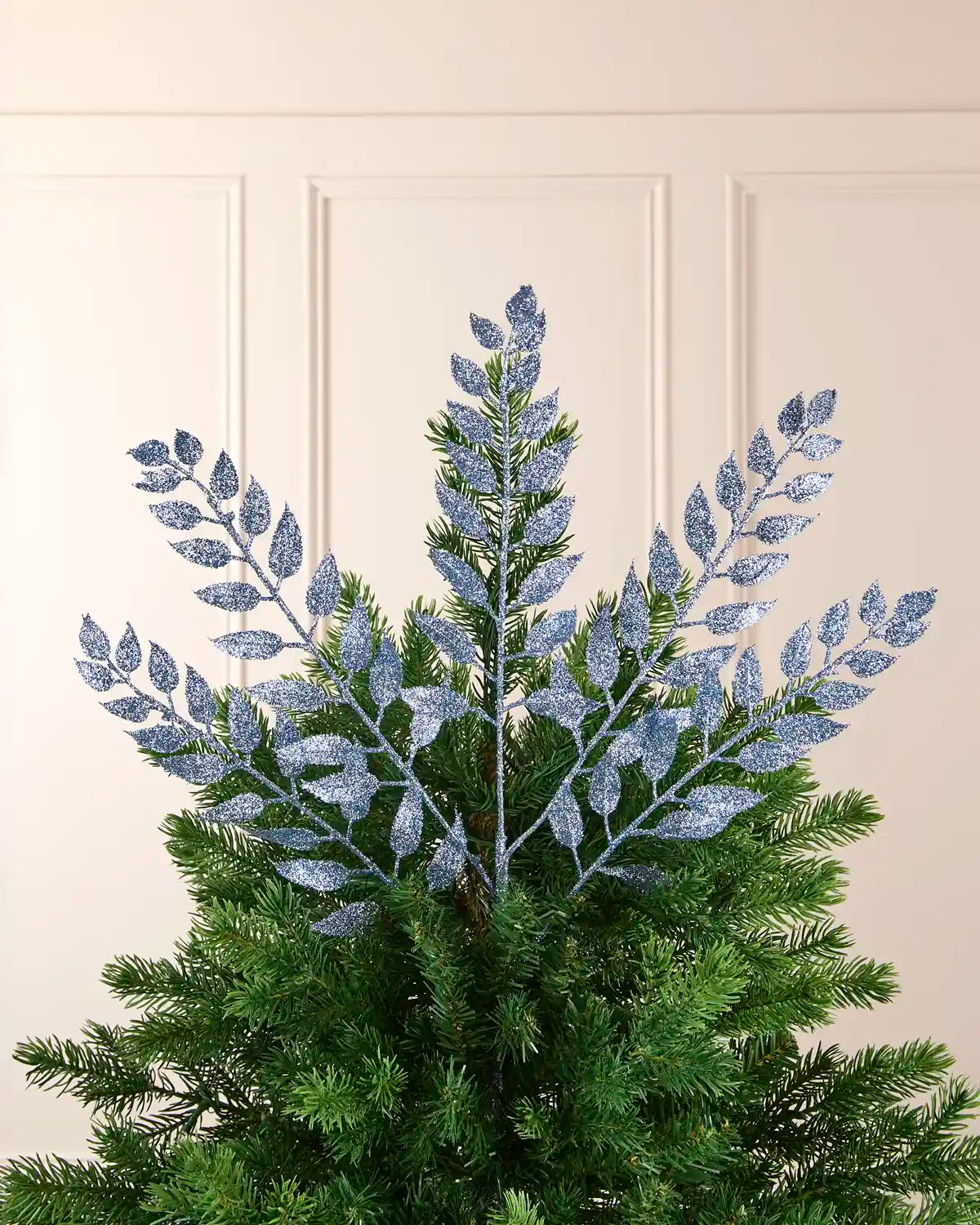 Ice blue leaf Christmas tree spray styled at the top of a green Christmas tree.
