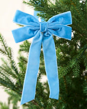 Ice blue 16.5 cm velvet double bow with long tails attached to a Christmas tree branch.