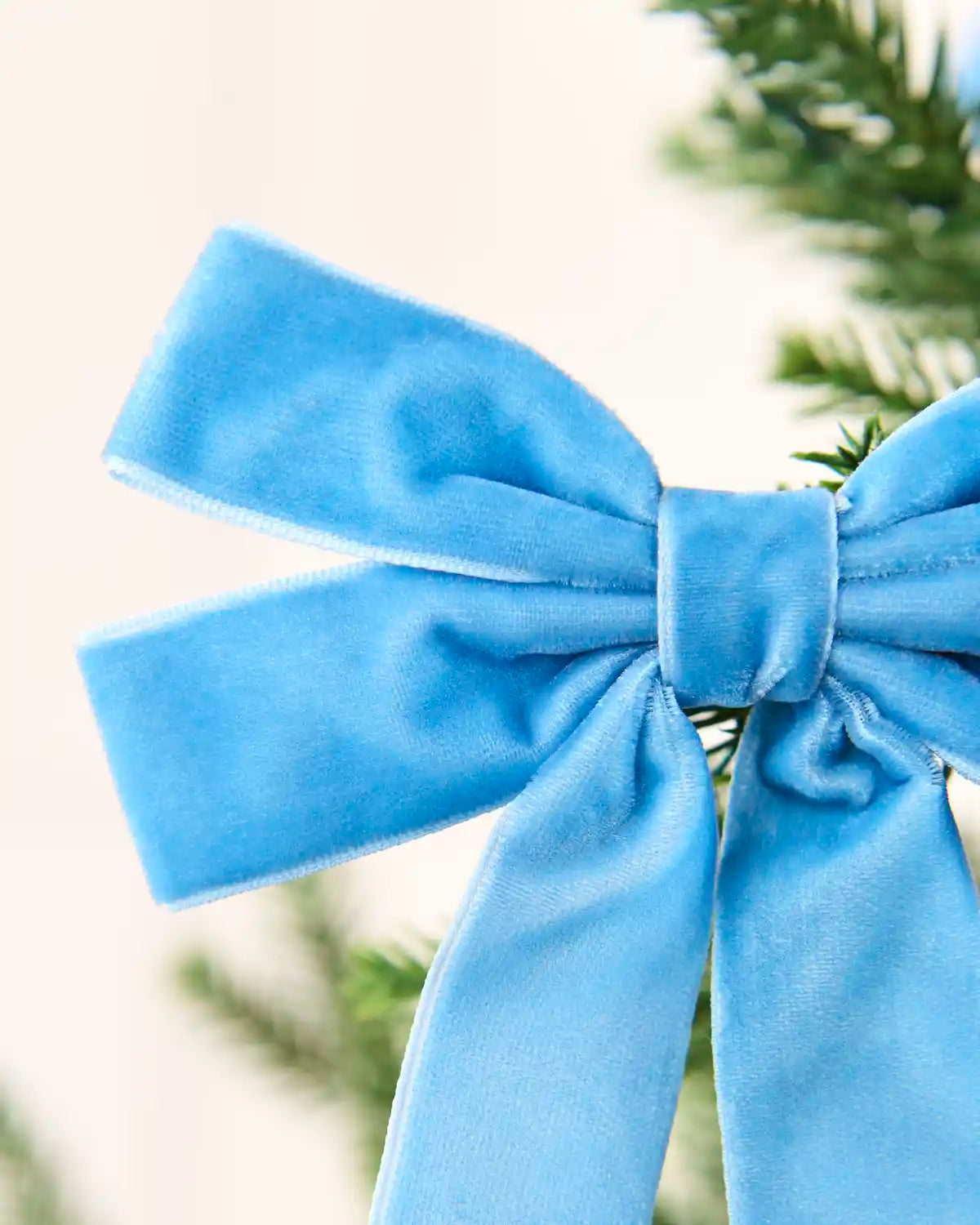 Close-up of an ice blue velvet double bow showing layered loops, long tails and soft texture.