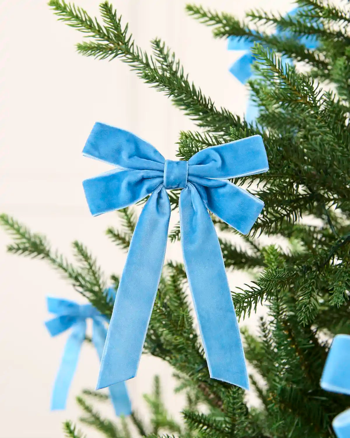 Ice blue velvet double bow displayed among matching bows on a Christmas tree.