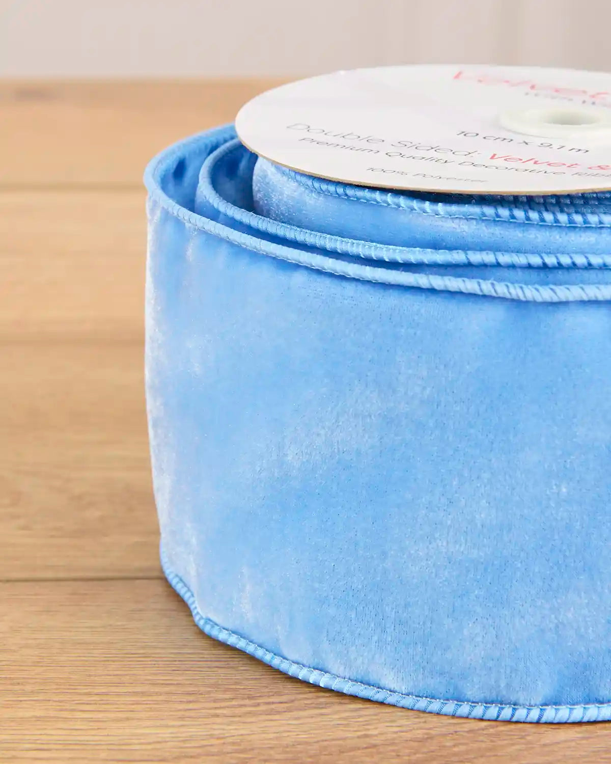 Close-up of 10 cm wide ice blue velvet ribbon showing its soft surface and wired edges.