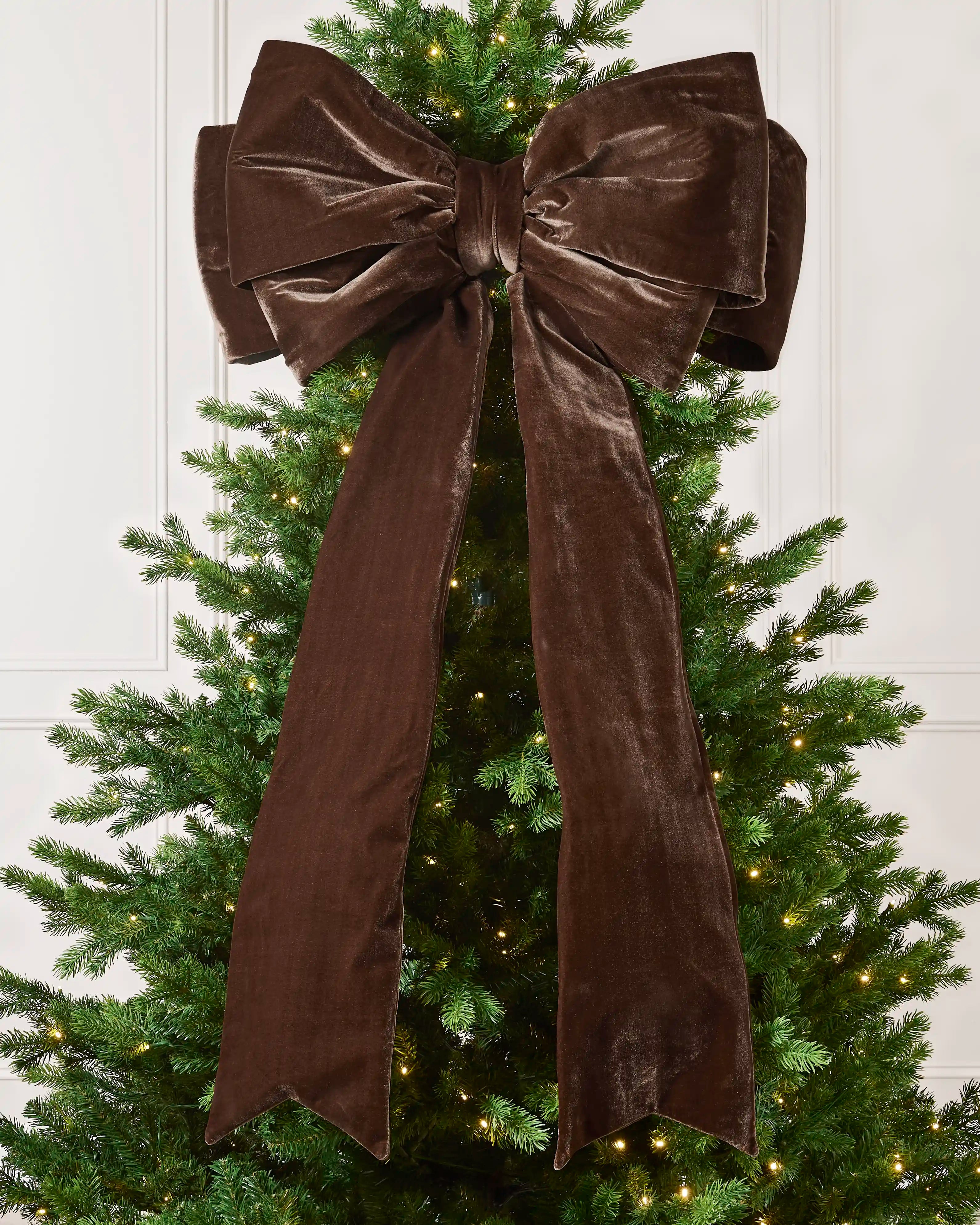 Large 140 cm espresso velvet Christmas bow displayed on a lit Christmas tree with long hanging tails.