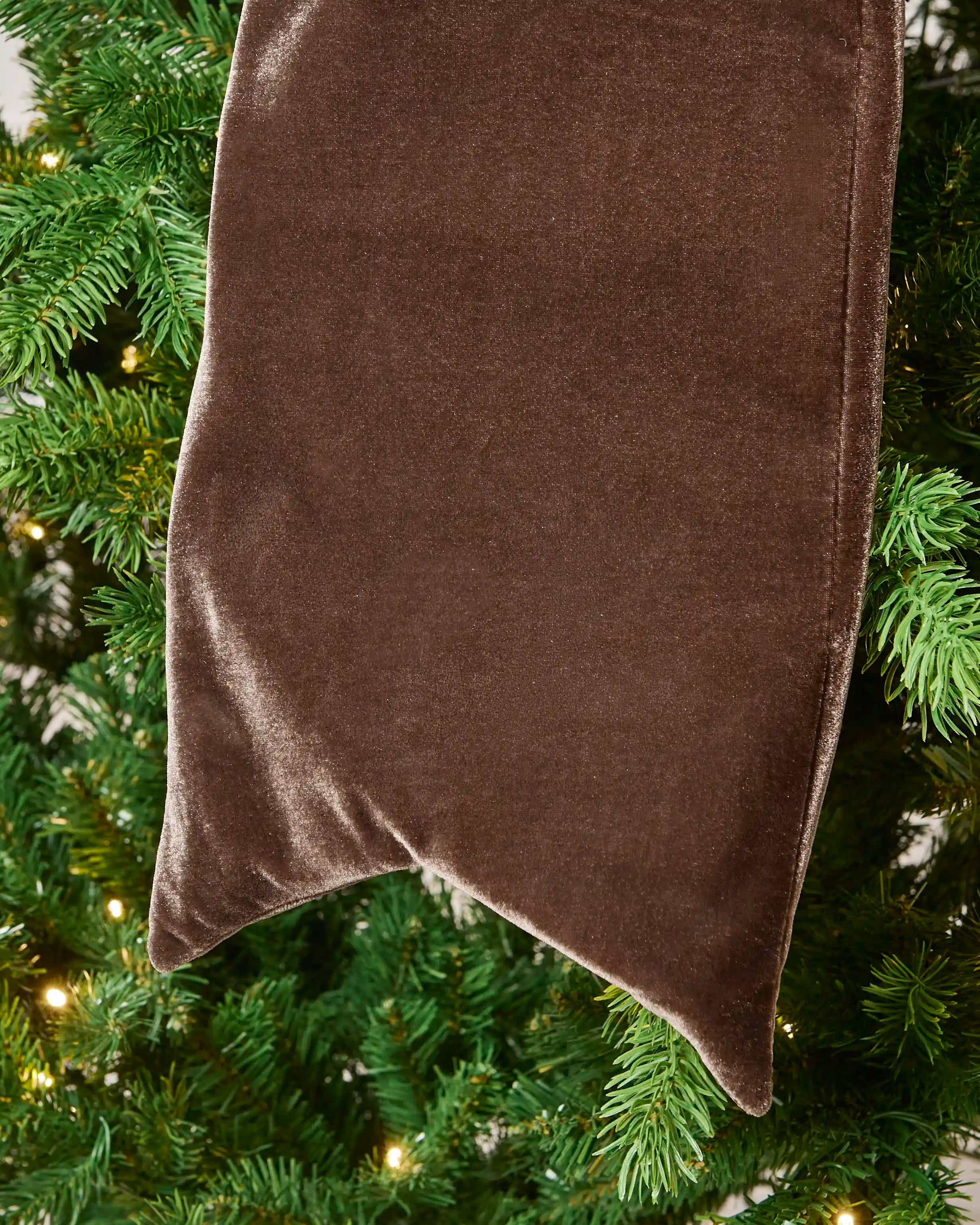 Close-up of the espresso velvet Christmas bow tail showing the soft fabric and pointed end.