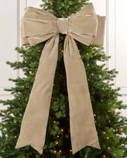 Large 140 cm latte velvet Christmas bow displayed on a lit Christmas tree with long hanging tails.