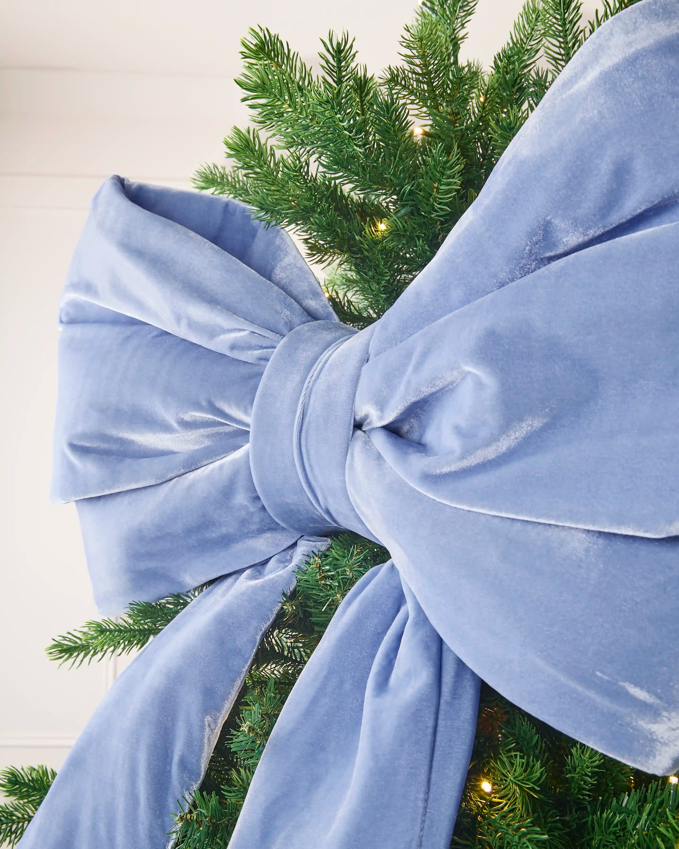 Close-up of the large ice blue velvet Christmas bow showing its full layered loops.