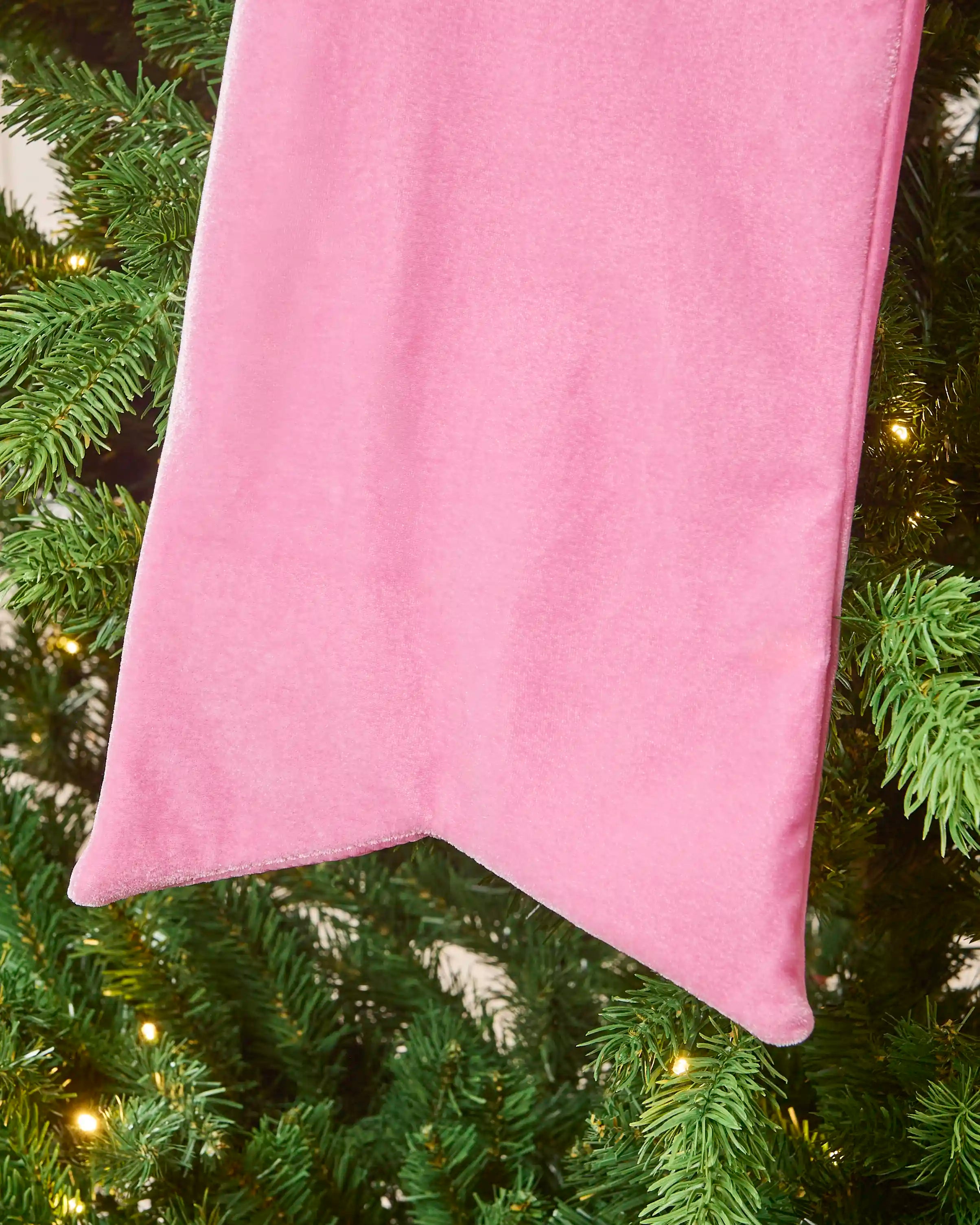 Close-up of the long pink velvet Christmas bow tail with a pointed finish.