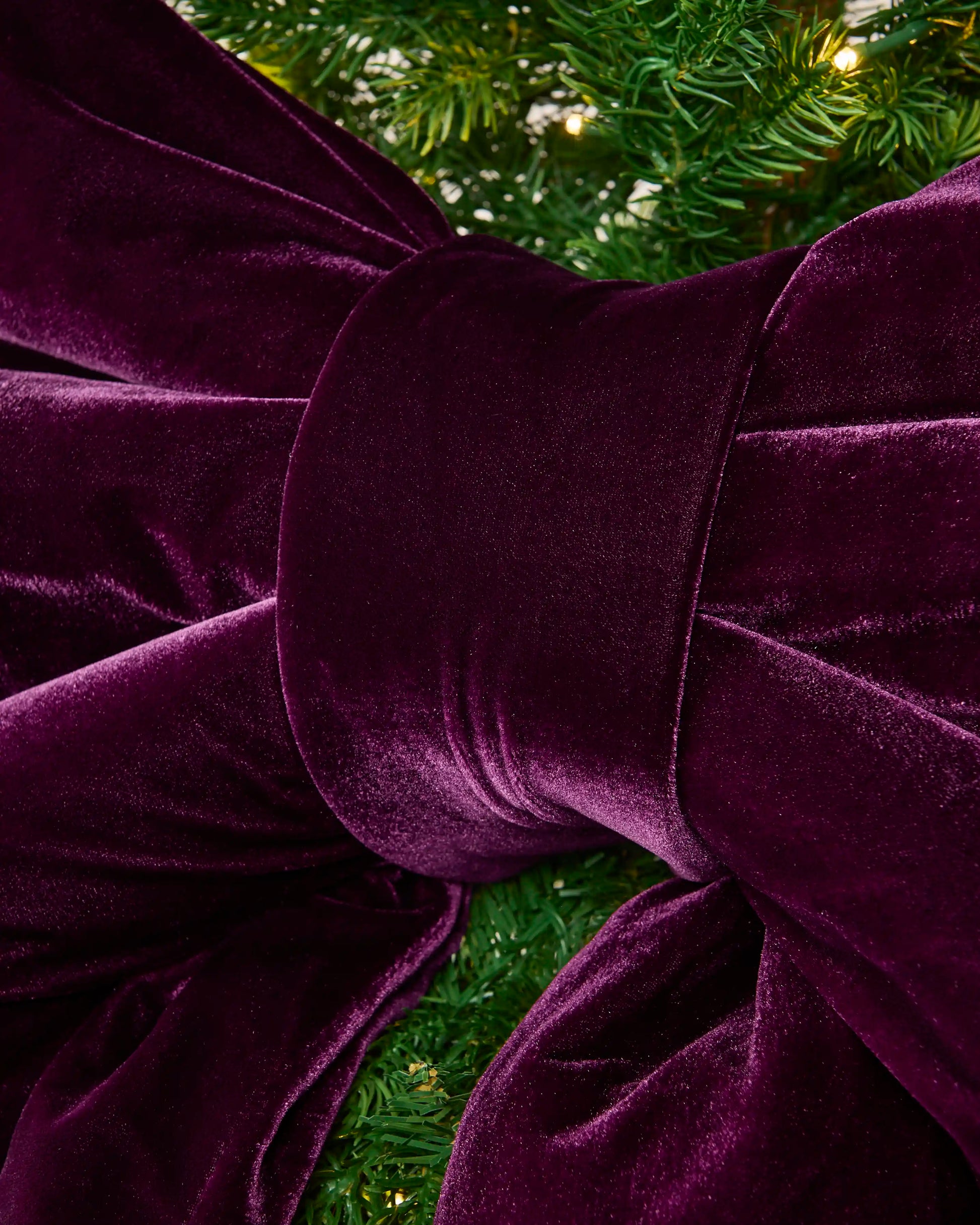 Close-up of the purple velvet Christmas bow showing the padded centre knot and gathered fabric.