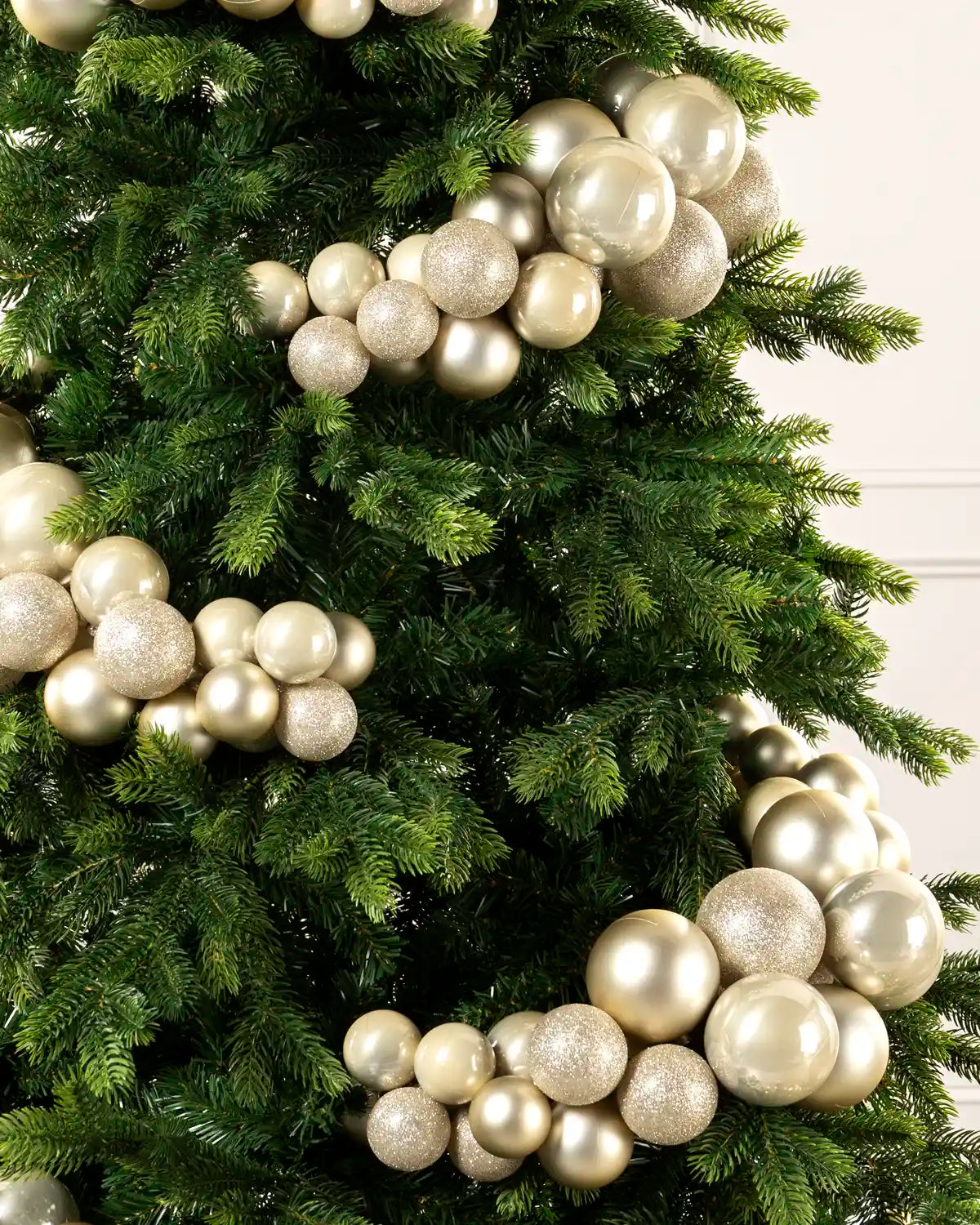 Close-up of latte bauble cluster arch on a Christmas tree showing mixed sizes and finishes.