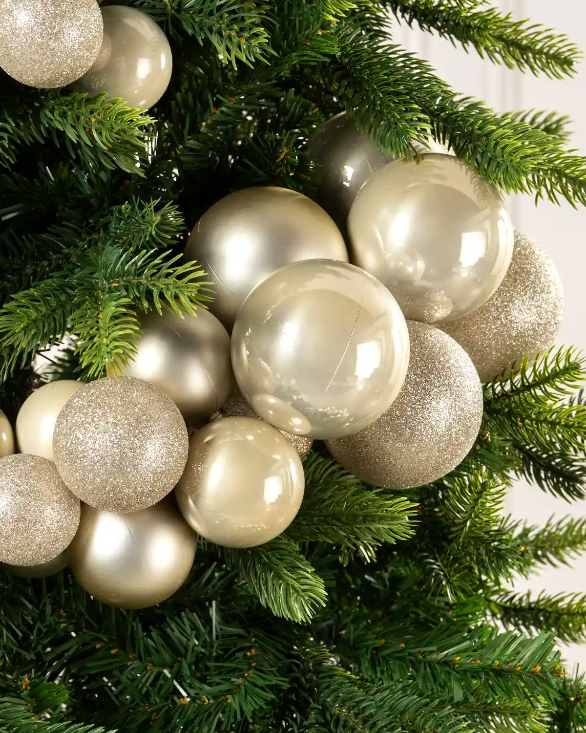 Latte bauble cluster arch arranged through the upper branches of a green Christmas tree.