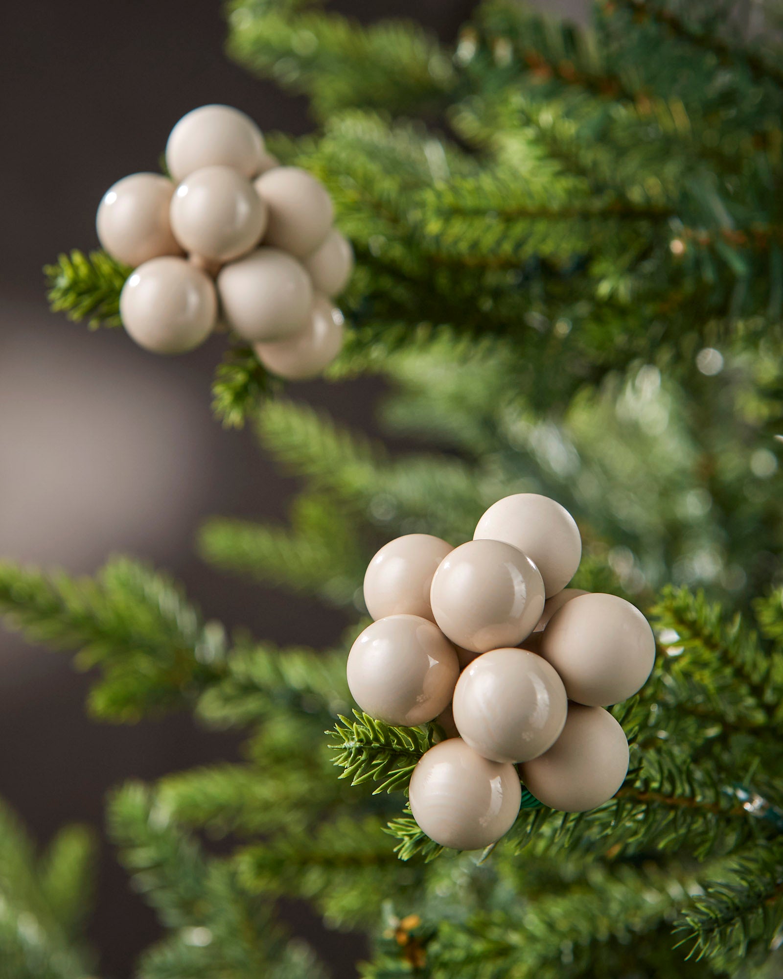Close-up of latte glass berry cluster baubles with matt and gloss finishes on a Christmas tree.