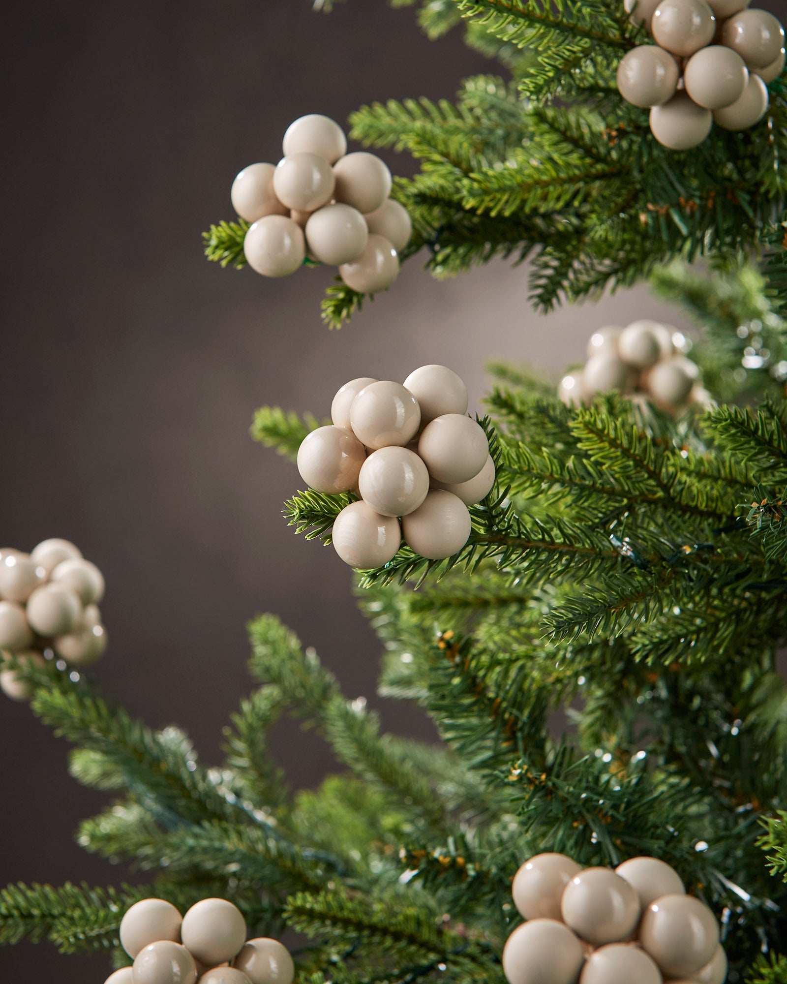 Latte glass berry cluster baubles arranged on a green Christmas tree.