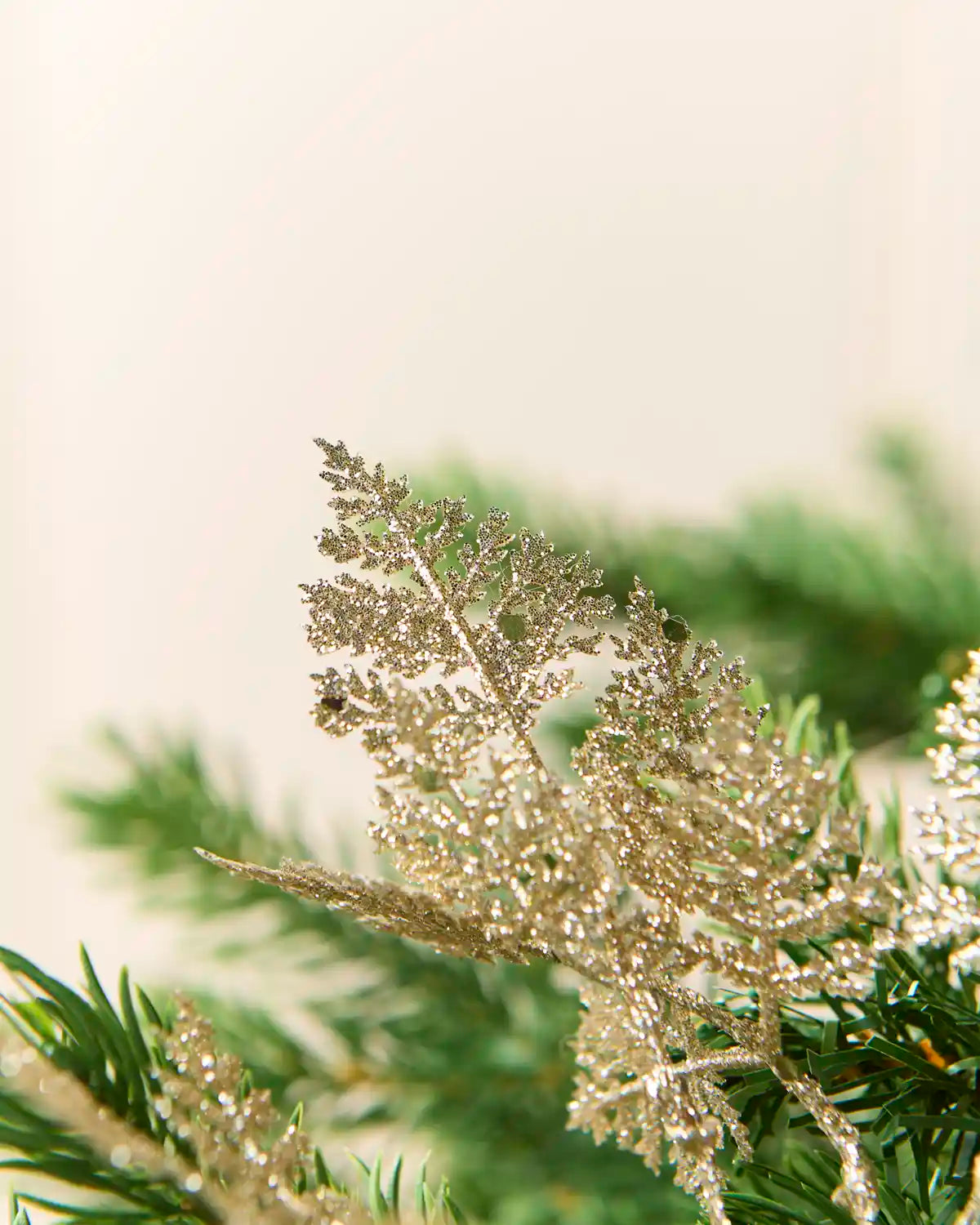 Latte glitter leaf picks displayed across green Christmas tree branches with clustered metallic leaves.