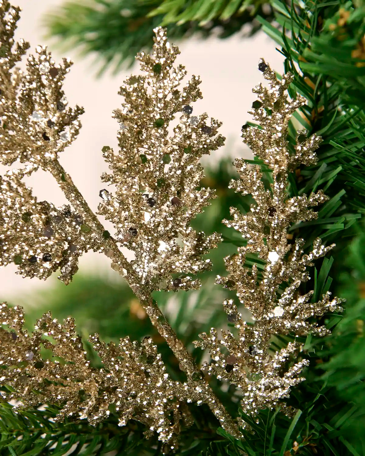 Latte glitter leaf pick with detailed branching displayed amongst Christmas tree greenery.