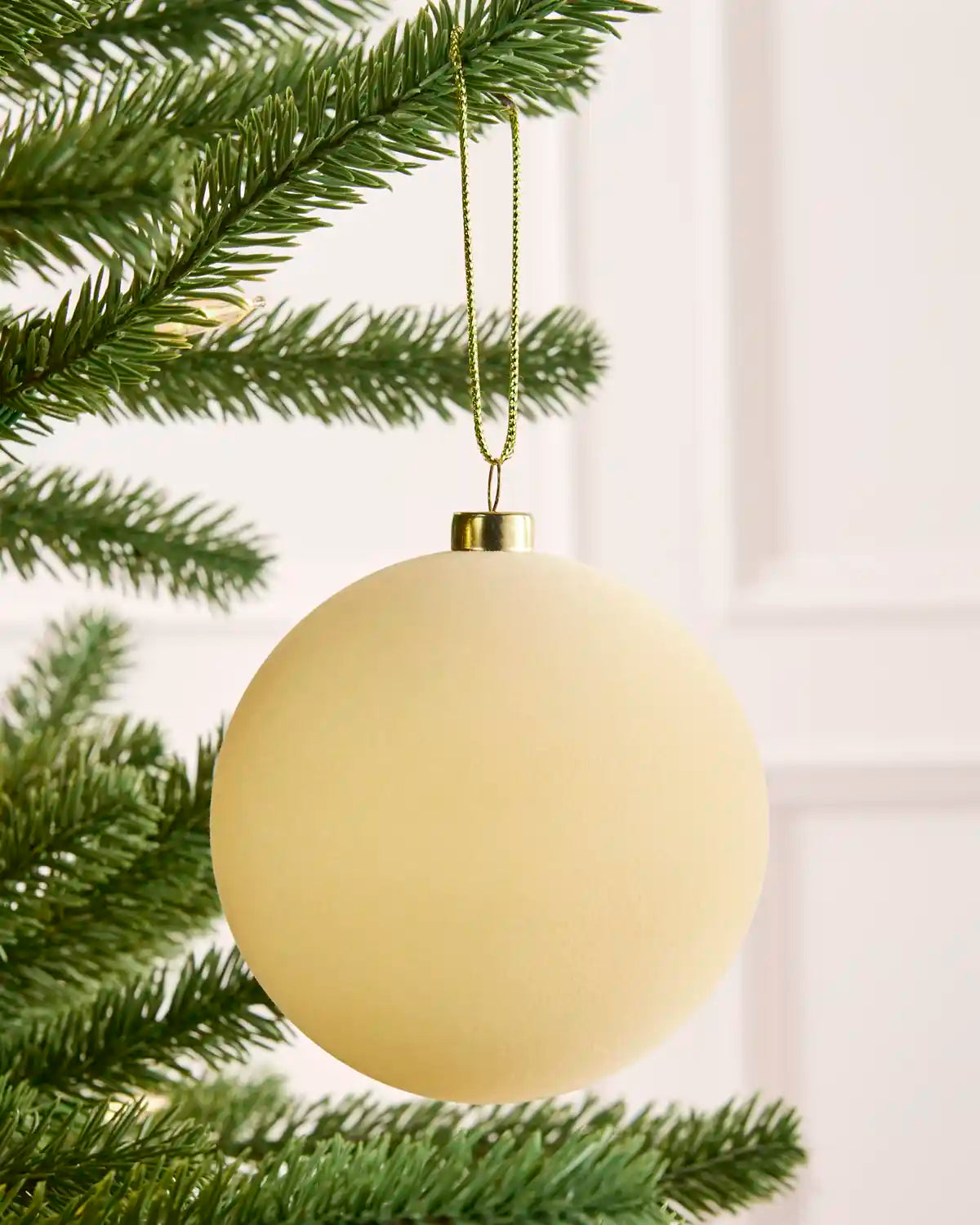 Close-up latte velvet round shape bauble hanging from Christmas tree