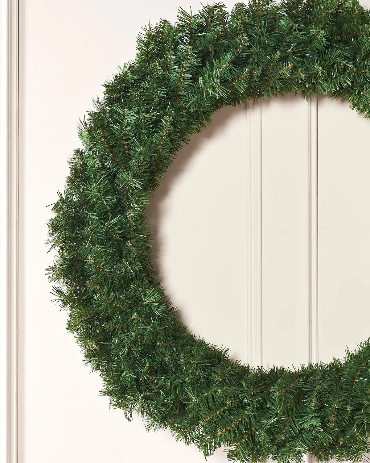 Close-up of the majestic wreath showing dense green foliage on a white door