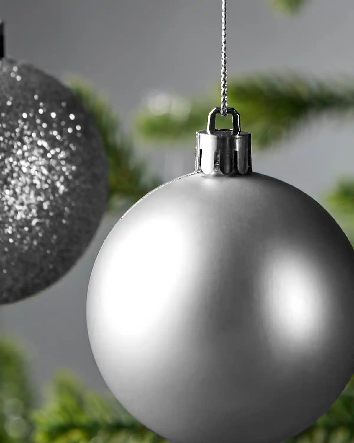 matt silver Christmas bauble hanging on a tree with a blurred background