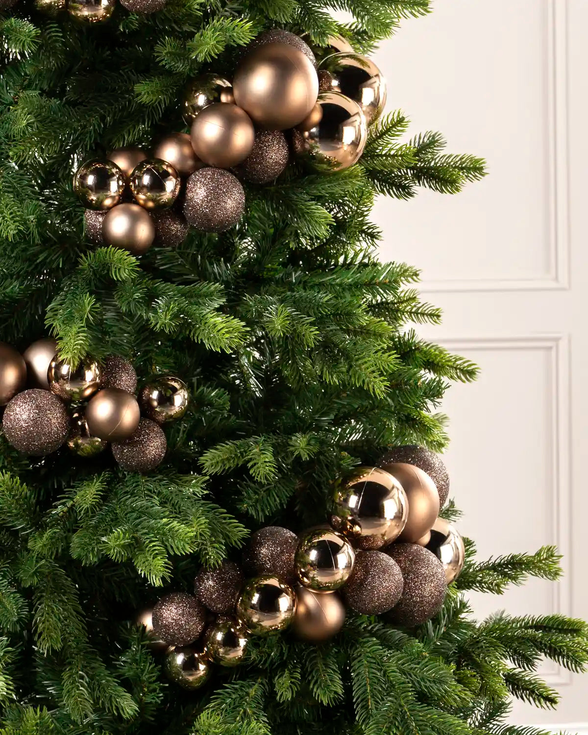 Close-up of mocha bauble cluster arch on a Christmas tree showing mixed sizes and finishes.