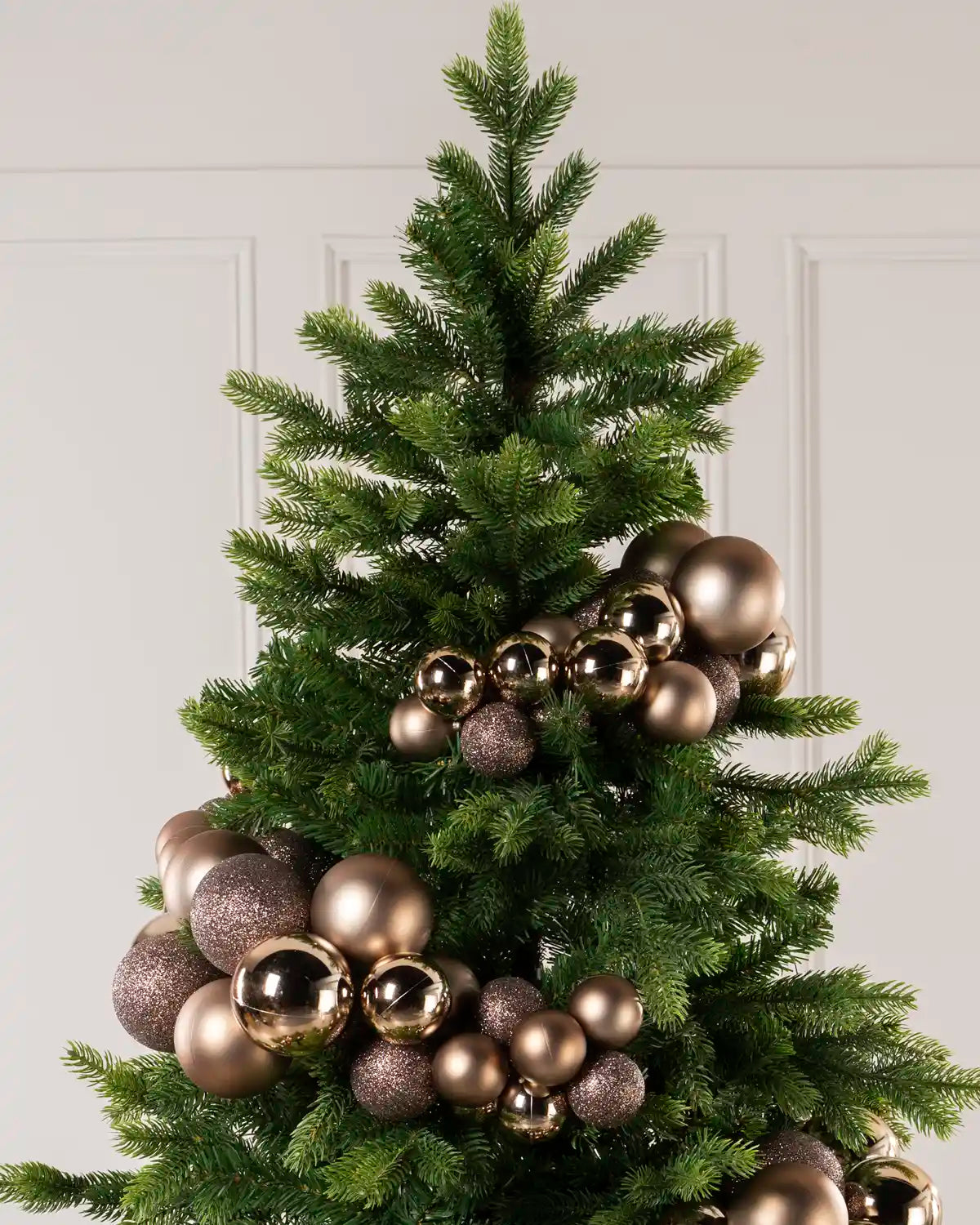 Mocha bauble cluster arch styled through the upper branches of a green Christmas tree.