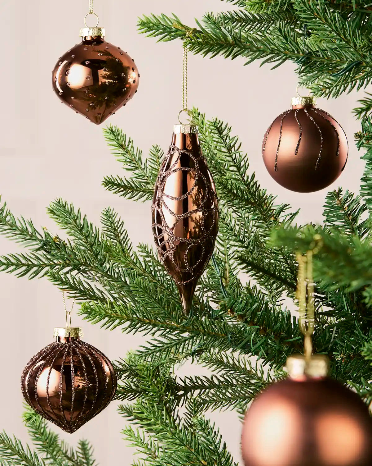 Mixed mocha glass baubles with matt, shiny and glitter finishes on a Christmas tree.