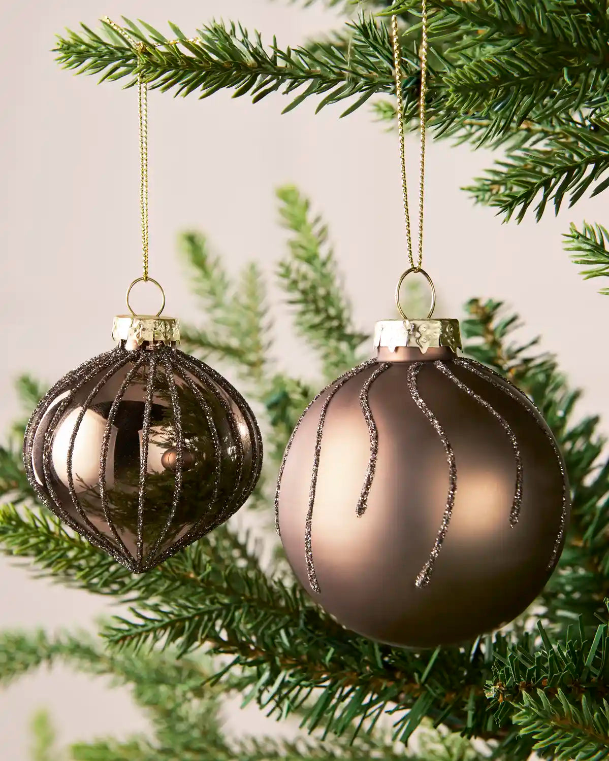 Close-up of mocha onion-shaped and round glass baubles with glitter stripe patterns.