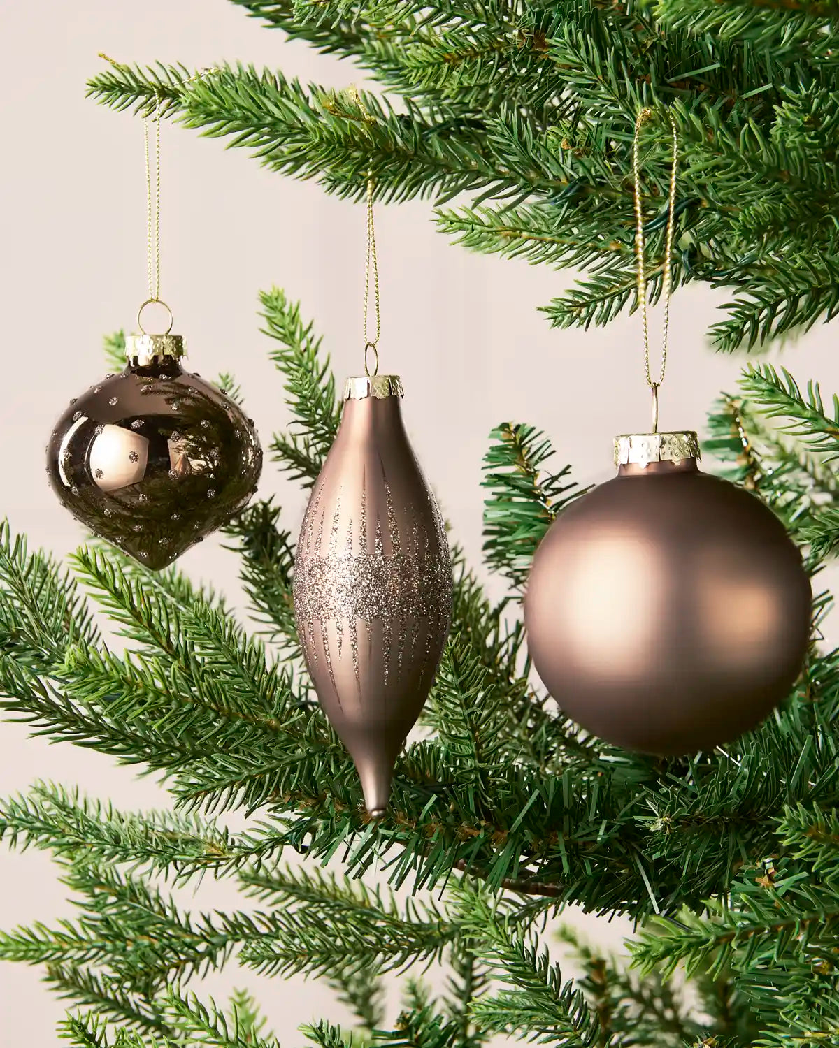 Mocha round, onion-shaped and teardrop glass baubles displayed on a Christmas tree.