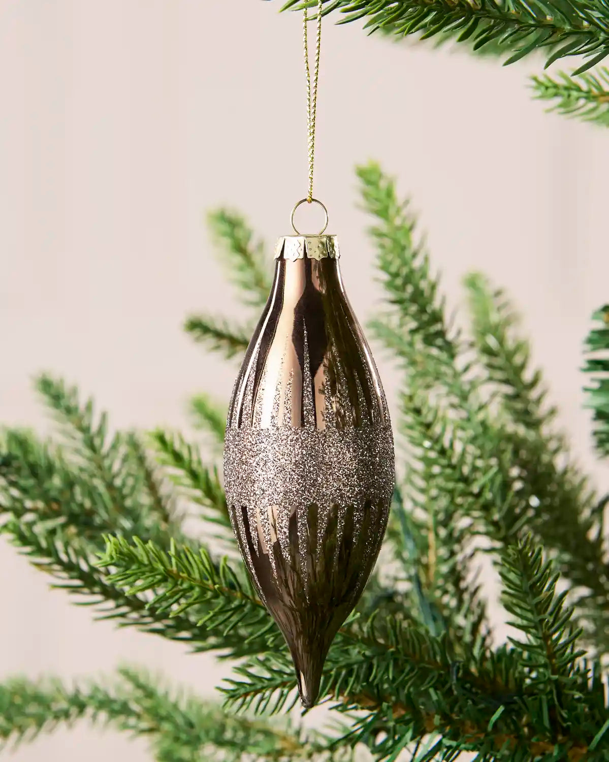 Close-up of a mocha teardrop glass bauble with glitter lines and a central glitter band.