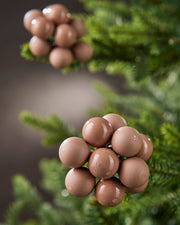 Close-up of mocha glass berry cluster baubles with matt and gloss finishes on a Christmas tree.