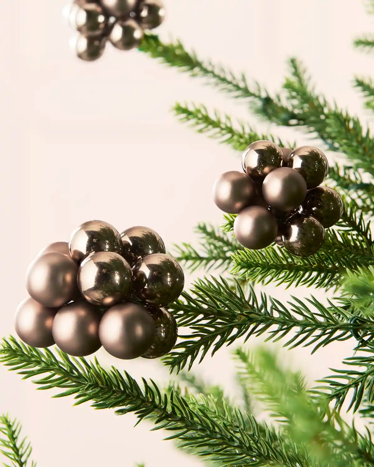 Close-up of mocha glass berry cluster baubles with shiny and matt finishes on a Christmas tree.