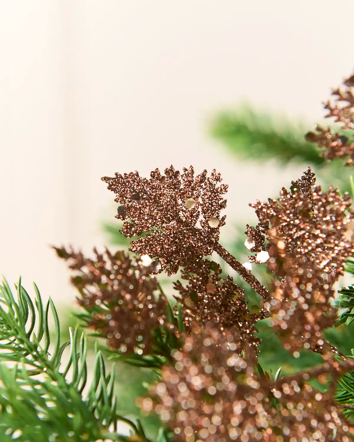 Mocha glitter leaf picks displayed across green Christmas tree branches with clustered metallic leaves.