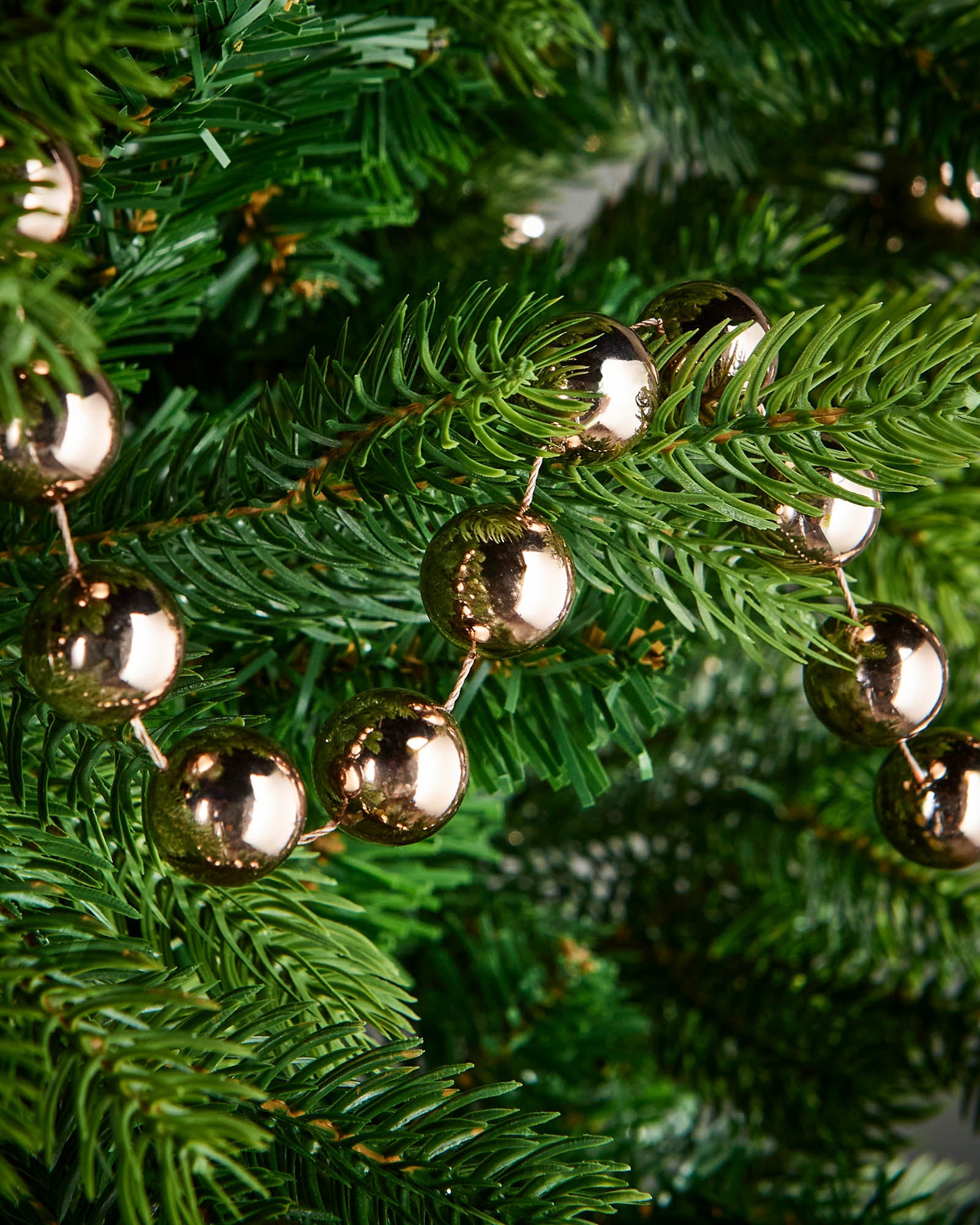 Close-up of glossy mocha beads on a beaded garland displayed on a Christmas tree.