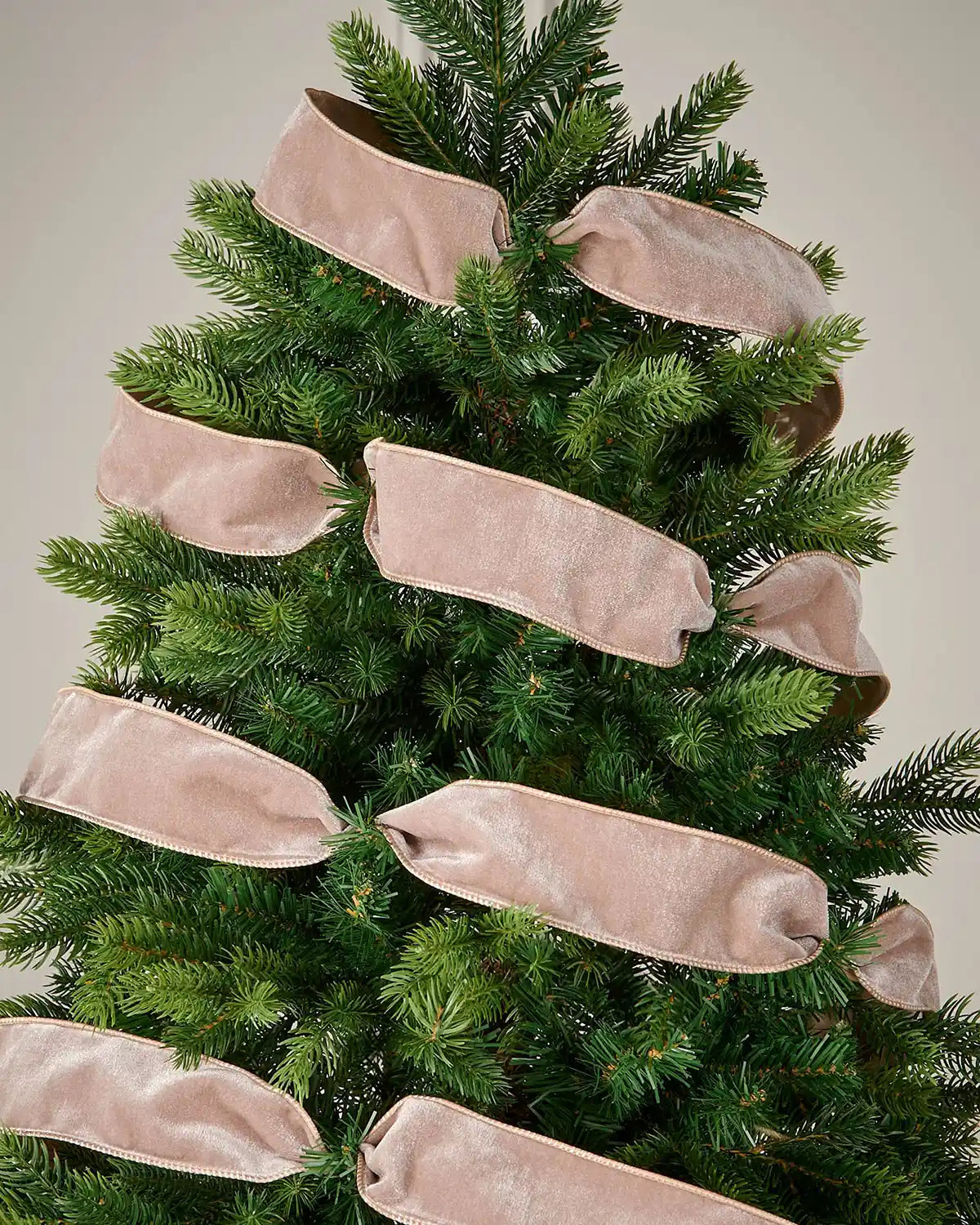Mocha wired velvet ribbon arranged in decorative loops around an artificial Christmas tree.