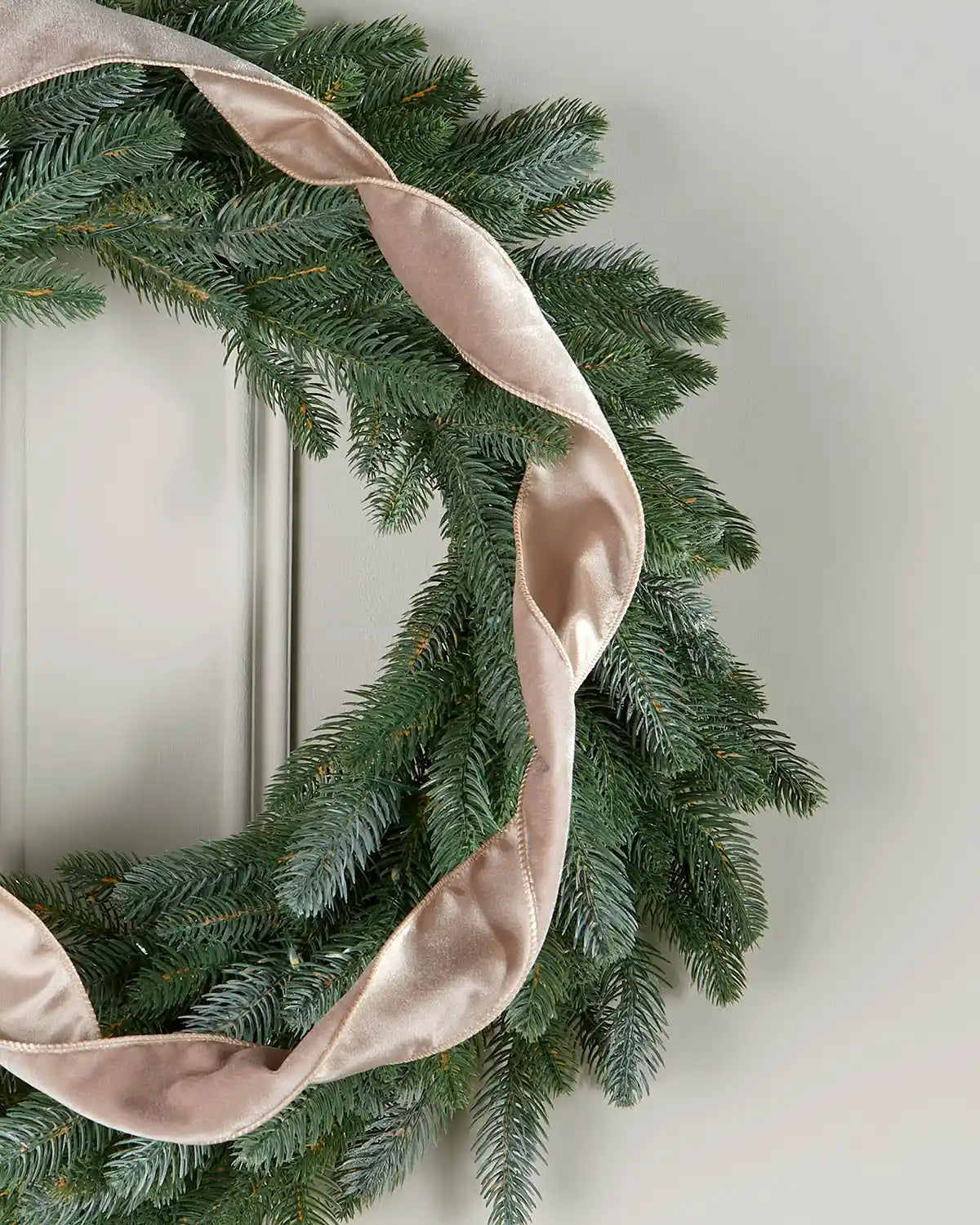 Mocha wired velvet ribbon woven through an artificial Christmas wreath to create soft structured loops.