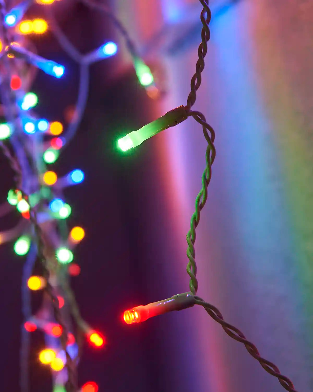 Close-up of red and green LED bulbs on multi-colour icicle lights with white cable.