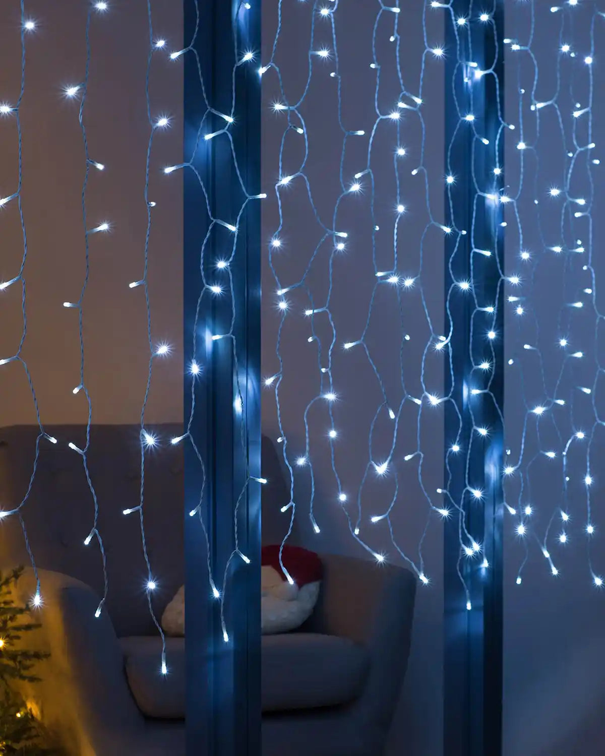 Bright white LED curtain lights hanging in a window for a festive indoor display