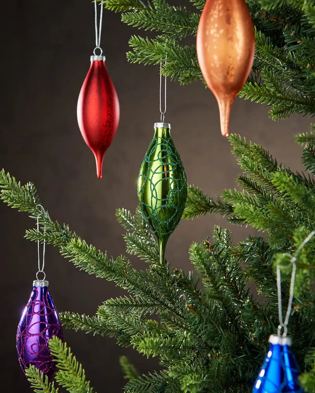 Multicolour glass finial baubles hanging on Christmas tree branches