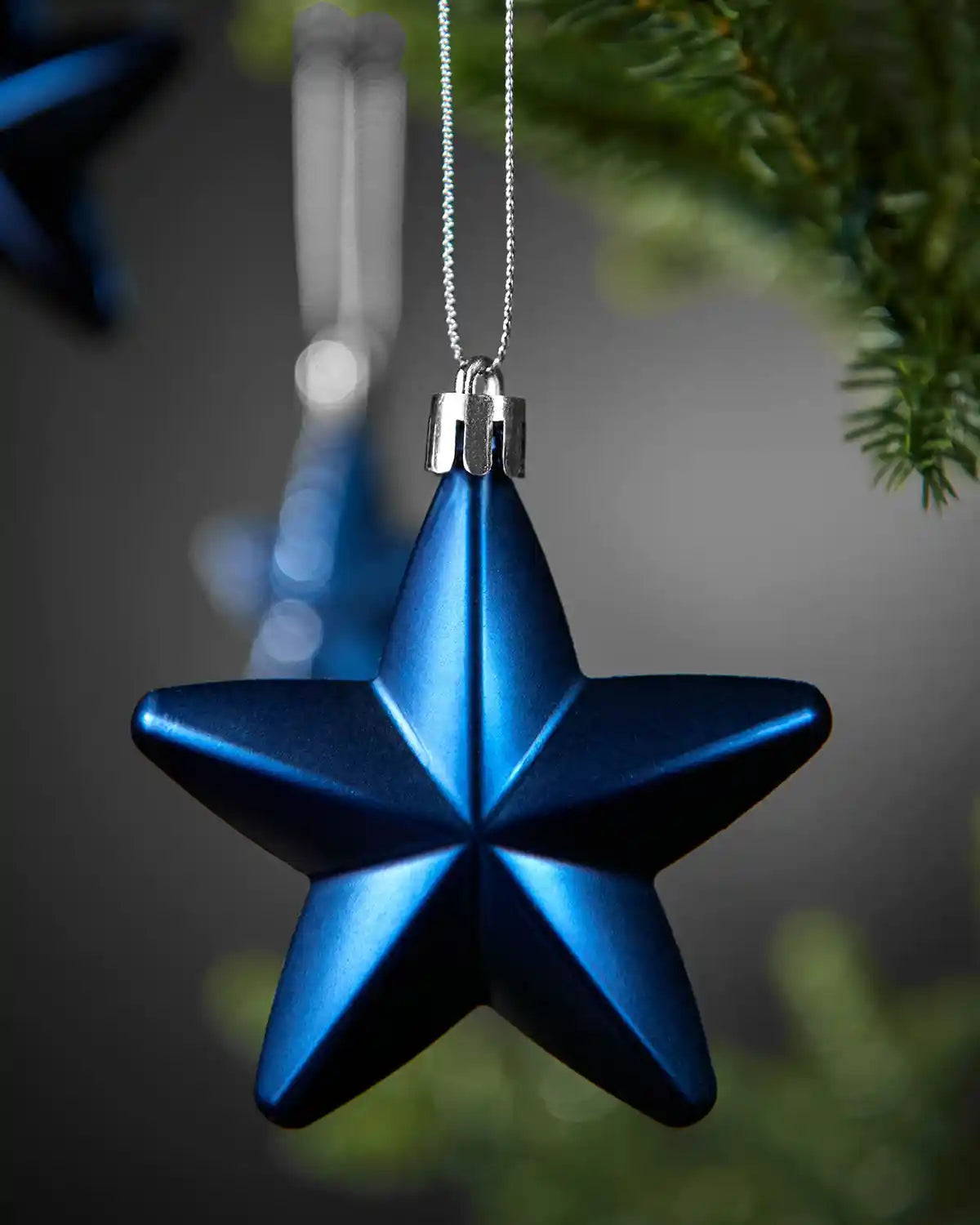 Close-up of a matte navy blue 7cm hanging star with silver string.